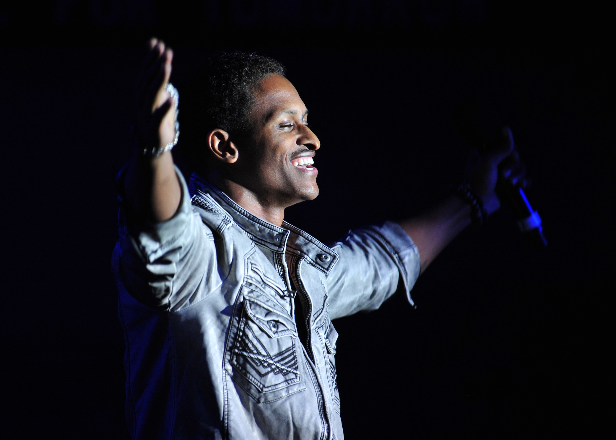 Jerome Wayne, (J Rome) vocalist for the 'Gift of Music' tour by Air Force Entertainment Group, performs for the crowd at a show for the 380th Air Expeditionary Wing at an undisclosed location in Southwest Asia, Dec. 19, 2013. Wayne was a member of the 2003 edition of Tops in blue. All of the performers are alumni of previous Tops in Blue shows. (U.S. Air Force photo by Staff Sgt. Michael Means/Released)