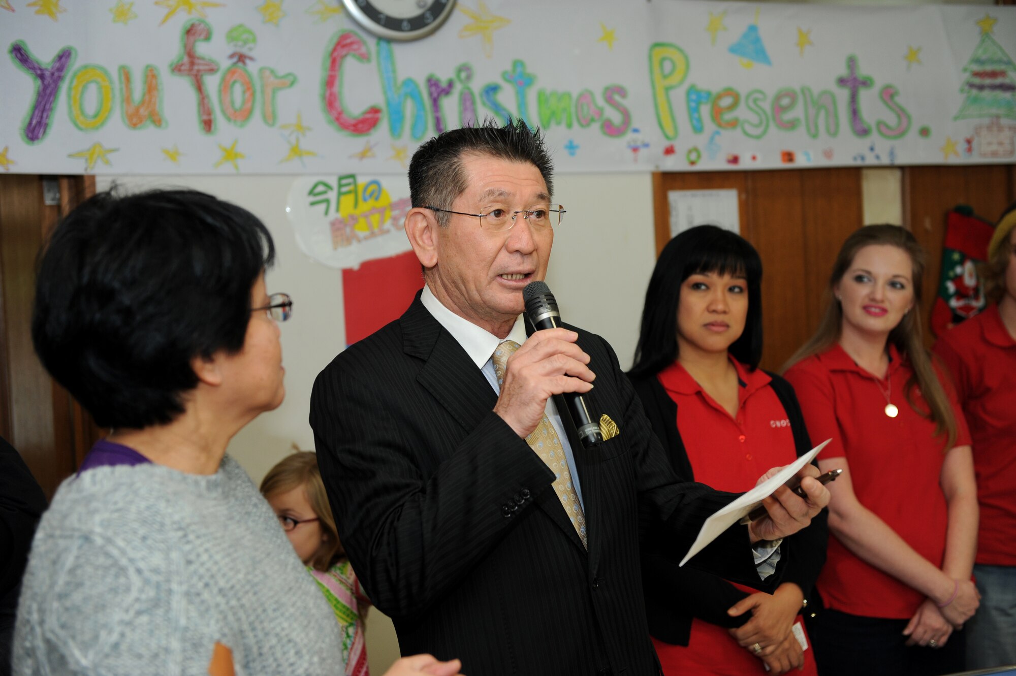 Hirokazu Inafuku, Okinawa Chuo Ikusei En facility for special needs director, speaks at the Christmas Drive on Okinawa, Japan, Dec. 20, 2013. Inafuku thanked the members of Kadena Air Base who were present at the event for their generosity and kindness for donating food and presents during the holiday season. (U.S. Air Force photo by Airman 1st Class Hailey R. Staker)