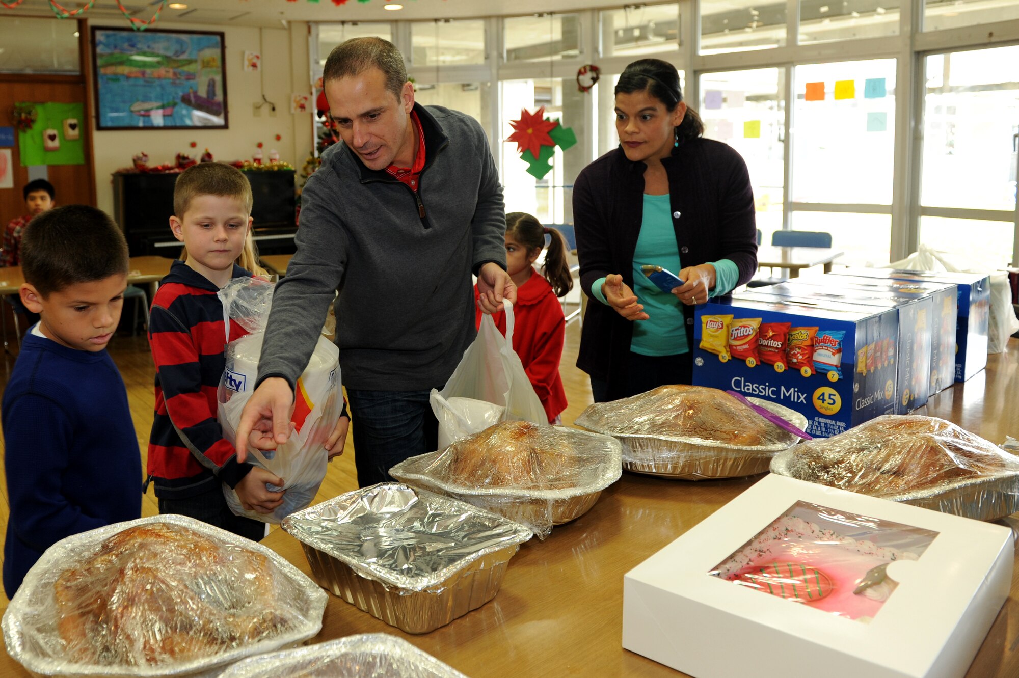 U.S. Air Force Lt. Col. Peter Gryzen, 18th Maintenance Group deputy commander, instructs children on where to place donations during a Christmas drive at the Okinawa Chuo Ikusei En facility for special needs on Okinawa, Japan, Dec. 20, 2013. Members of Kadena Air Base donated food and presents as part of an exchange for members with special needs during the holiday season. (U.S. Air Force photo by Airman 1st Class Hailey R. Staker)