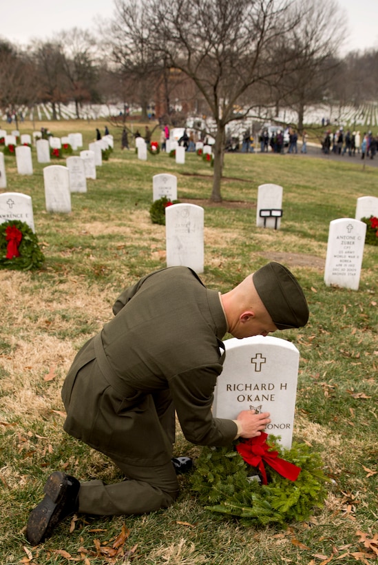 Pvt. Chad Neuzil, a student with Marine Corps Combat Support Service Schools, wipes off of Medal of Honor recepient Richard O'Kane's headstone in Arlington National Ceremony after placing a wreath under it during Wreaths Across America Day, Dec. 11. O'Kane served as a rear admiral in the Navy and was awarded the Medal of Honor during World War II. 