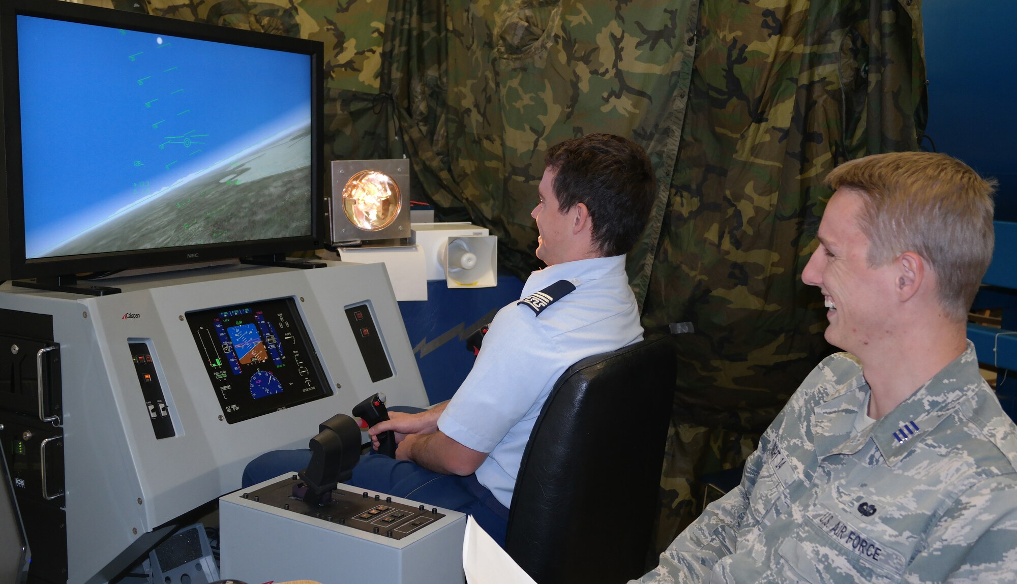 Cadet 1st Class Carson Fugal uses a flight simulator while Cadet 1st Class Blake Albrecht asks questions about research into how pilots handle nose and light and a
deterrent to keep birds away from an aircraft./Air Force Photo,
