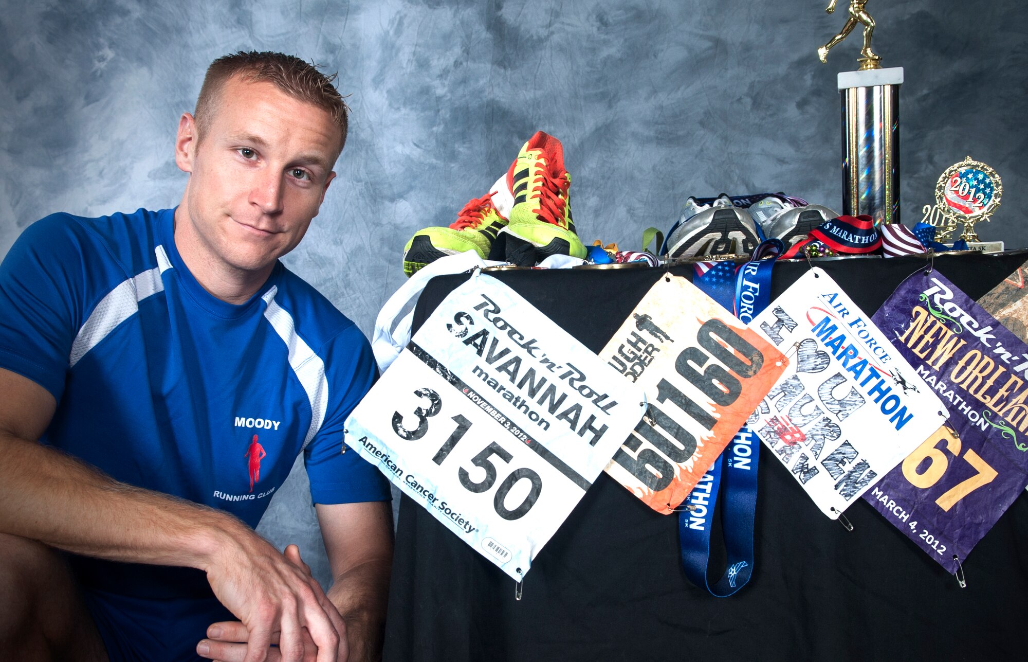 U.S. Air Force Tech. Sgt. Aaron Williams, 372nd Training Squadron Det. 9 instructor, poses next to his racing bibs and awards from previous marathons at Moody Air Force Base, Ga., Dec. 23, 2013. Since 2010, Williams has run nine full marathons. (U.S. Air Force photo by Senior Airman Eileen Meier/Released)