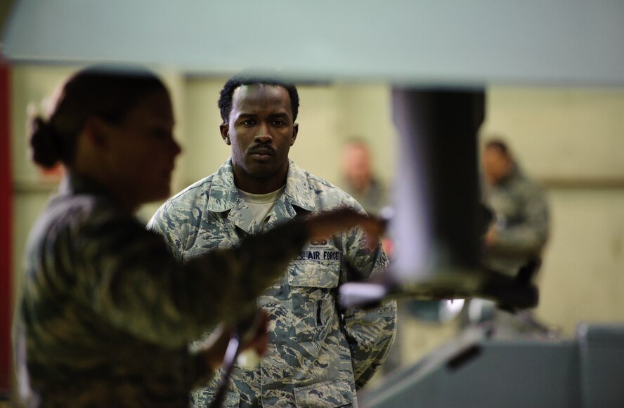 Senior Airman Demeterius White, 8th Maintenance Squadron Weapons Standardization Section, watches a load crew member prepare to install a weapon at Kunsan Air Base, Republic of Korea, Dec. 20, 2013. The 8th MXS WSS helps train Airmen to load munitions and test those skills during quarterly competitions. (U.S. Air Force photo by Senior Airman Armando A. Schwier-Morales/Released) 