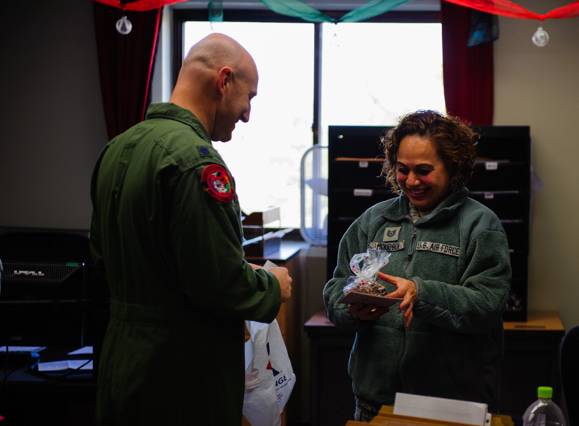 Lt. Col. Travis Rex, 8th Operations Support Squadron commander, hands a holiday treat bag to Tech. Sgt. Roseann McKibben, 8th Operations Support Squadron, at Kunsan Air Base, Republic of Korea, Dec. 24, 2013. The treats were donated by families wanting to show their support for the Wolf Pack. Base Leadership volunteered to help spread holiday cheer throughout the base with a variety of events from passing out packages at the base post office to giving treats to their squadrons.  (U.S. Air Force photo by Senior Airman Armando A. Schwier-Morales)