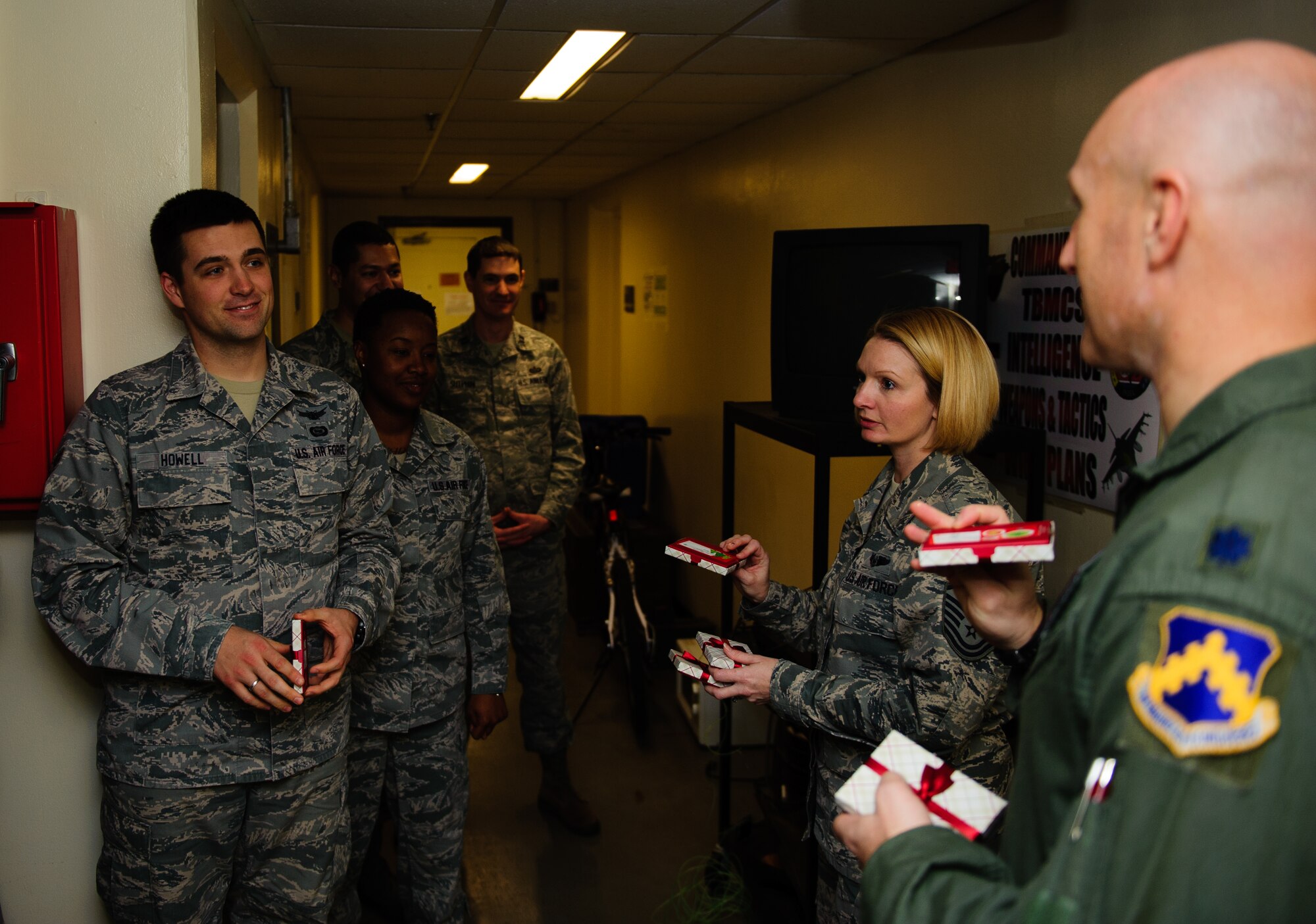 Lt. Col. Travis Rex, 8th Operations Support Squadron commander, and Master Sgt. Richelle Baker, 8th Operations Group first sergeant, hand a holiday treat to 8th Operations Support Squadron Airmen at Kunsan Air Base, Republic of Korea, Dec. 24, 2013. The treats were donated by families wanting to show their support for the Wolf Pack. Base Leadership volunteered to help spread holiday cheer throughout the base with a variety of events from passing out packages at the base post office to giving treats to their squadrons. (U.S. Air Force photo by Senior Airman Armando A. Schwier-Morales)