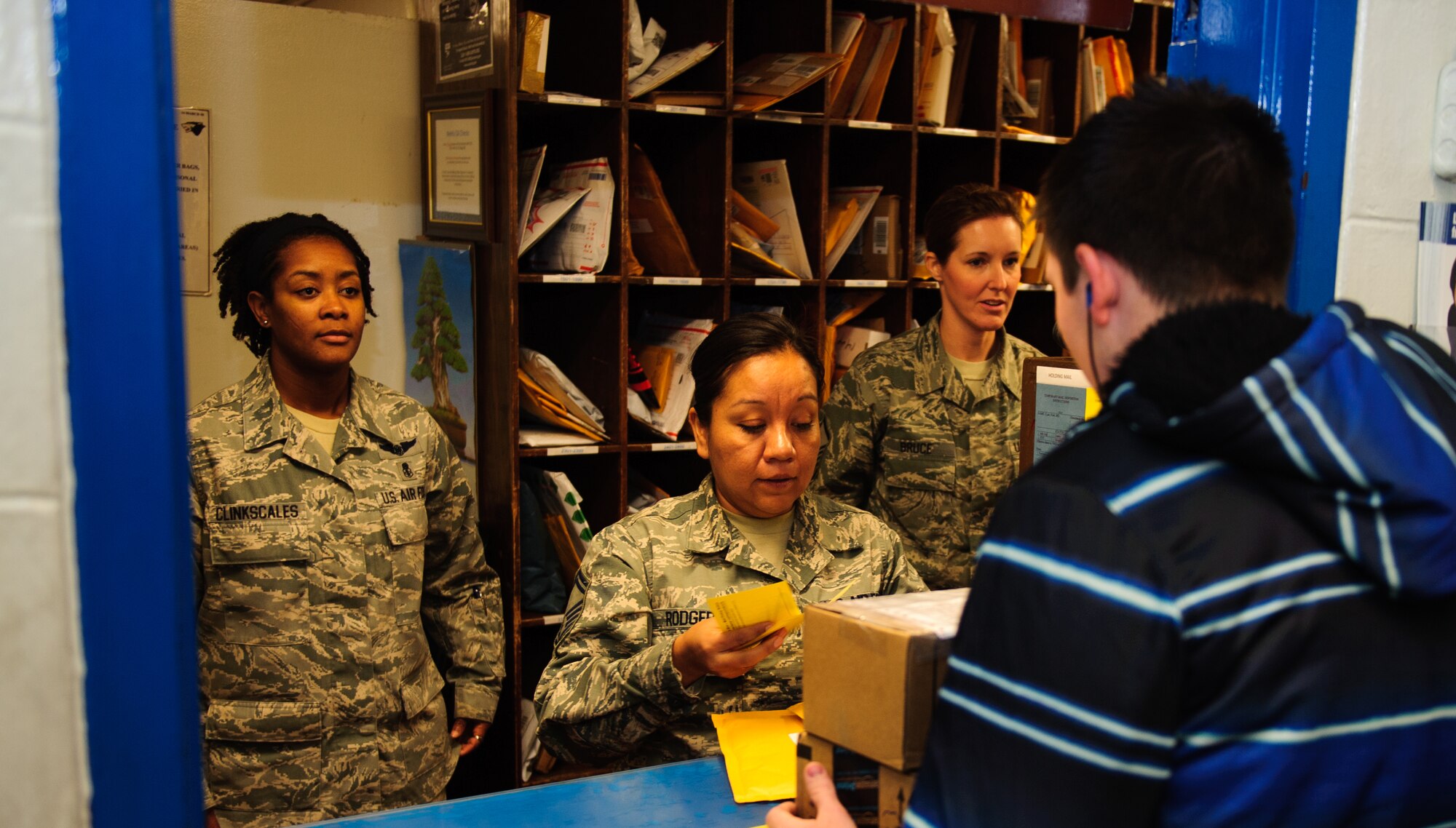 Master Sgt. Temekia Clinkscales, 8th Civil Engineer Squadron first sergeant, left, Senior Master Sgt. Eva Rodgers, 8th Comptroller Squadron superintendent, middle and Master Sgt. Charisse Bruce, 8th Logistic Readiness Squadron first sergeant, give a package to an Airman at Kunsan Air Base, Republic of Korea, Dec. 24, 2013. Base Leadership volunteered to help spread holiday cheer throughout the base with a variety of events from passing out packages at the base post office to giving treats to their squadrons. (U.S. Air Force photo by Senior Airman Armando A. Schwier-Morales) 