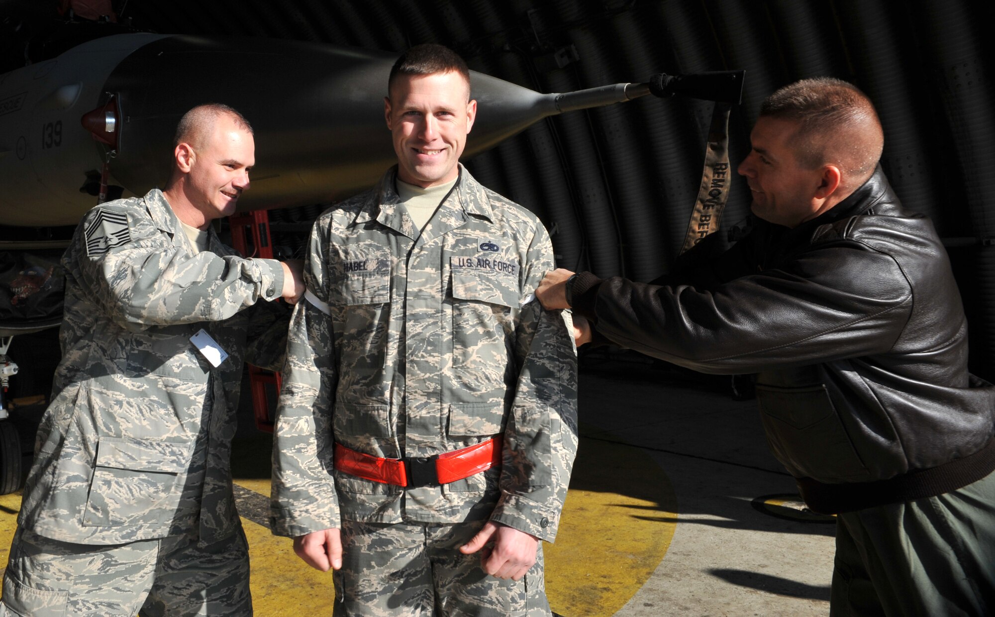 Col. Brook Leonard, 51st Fighter Wing commander, and Chief Master Sgt. Derrick Grames, 51st Mission Support Group chief, tack technical sergeant stripes on Staff Sgt. Allan Habel, 36th Aircraft Maintenance Unit crew chief, on the flight line at Osan Air Base, Republic of Korea, Dec. 23, 2013. Habel received a Stripes for Exceptional Performers promotion to the rank of technical sergeant – the only 51st FW Airman to receive a STEP promotion in 2013. (U.S. Air Force photo/Airman 1st Class Ashley J. Thum)