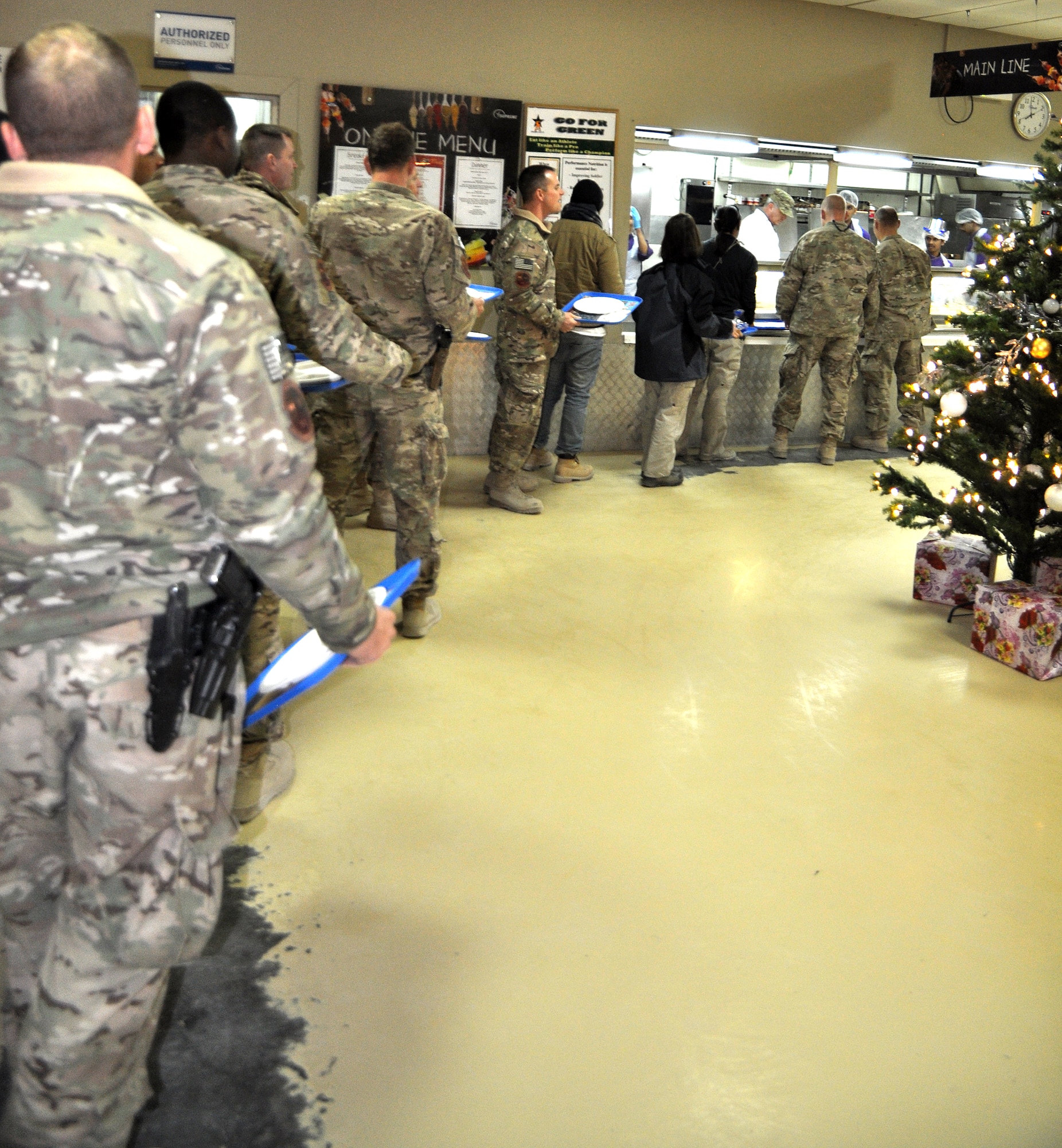 Service members and contractors wait in line for a Christmas meal at the Luxembourg Dining Facility, Kandahar Airfield, Afghanistan, Dec. 25, 2013. The meal included traditional Christmas foods like turkey, prime rib, stuffing and deserts. (U.S. Air Force photo by Capt. Jason Smith)