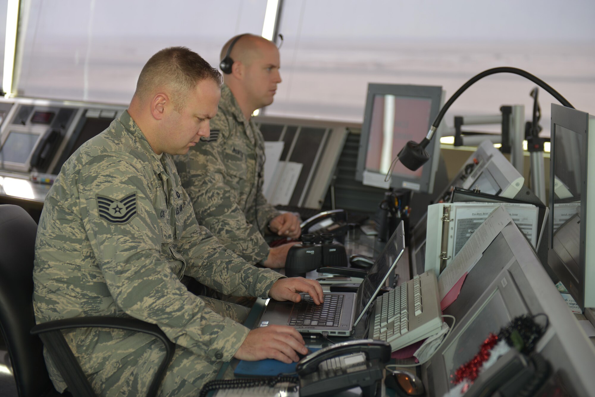 Tech. Sgt. Creighton Cope and Staff Sgt. Sean Bunten maintain surveillance of the flightline from the air traffic control tower at the 379th Air Expeditionary Wing in Southwest Asia, Dec. 24, 2013. Creighton and Bunten are 379th Expeditionary Operations Support Squadron air traffic controllers who help provide 24-hour support to aircraft in flight and on the flightline. Creighton is deployed from Little Rock Air Force Base, Ark., and a Tyler, Texas native. Bunten is deployed from Travis Air Force Base, Calif., and a Portland, Ore., native. (U.S. Air Force photo by Master Sgt. David Miller)