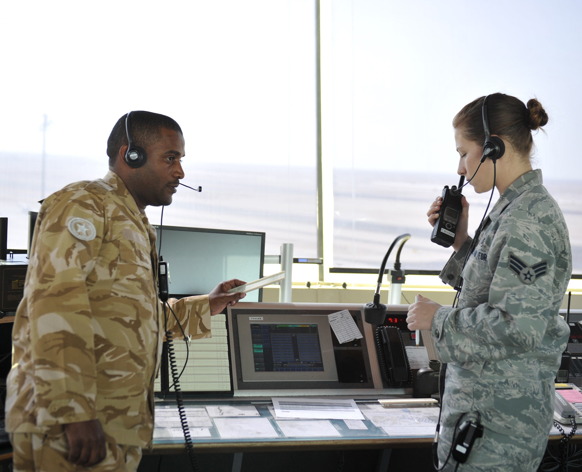 Senior Airman Rachael Plantz and Mohammmed S. Al-Hagri coordinate air traffic in the air traffic control tower at the 379th Air Expeditionary Wing in Southwest Asia, Dec. 18, 2013. Plantz and Al-Hagri are air traffic controllers who help provide 24-hour support to aircraft in flight and on the flightline. Al-Hagri is a host nation air traffic controller and Plantz is a 379th Expeditionary Operations Support Squadron air traffic controller deployed from Lackland Air Force Base, Texas, and a Fort Collins, Colo., native. (U.S. Air Force photo by Master Sgt. David Miller)