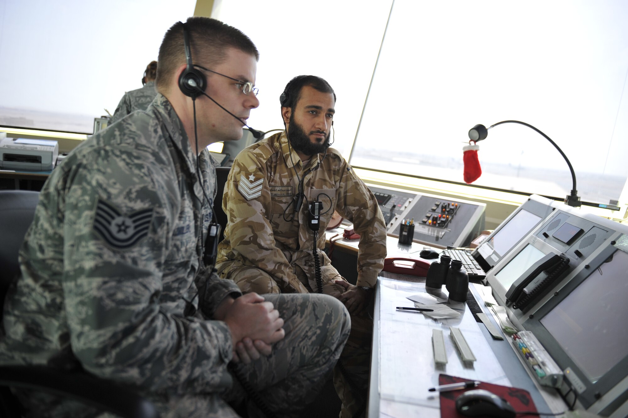 Tech. Sgt. Thomas Miller and Ahmed-Abdullah Al-Janahi maintain surveillance in the air traffic control tower at the 379th Air Expeditionary Wing in Southwest Asia, Dec. 18, 2013. Miller and Al-Janahi are air traffic controllers who help provide 24-hour support to aircraft in flight and on the flightline. Al-Janahi is a host nation air traffic controller and Miller is a 379th Expeditionary Operations Support Squadron air traffic controller deployed from Whiteman Air Force Base, Mo., and an Olathe, Kan., native. (U.S. Air Force photo by Master Sgt. David Miller)