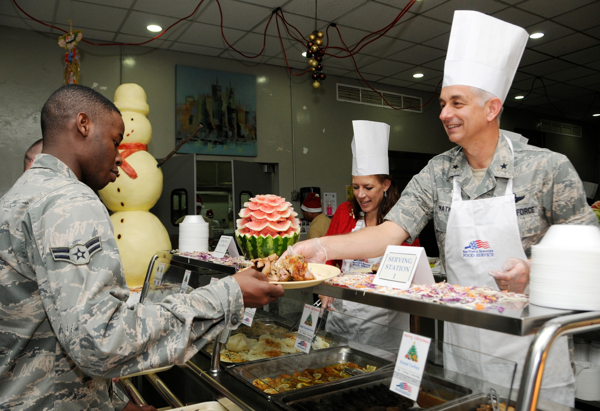 Brig. Gen. Roger H. Watkins and his wife Leslie serve Christmas Day meals to service members at the 379th Air Expeditionary Wing in Southwest Asia, Dec. 25, 2013. Senior leadership volunteered throughout the day to serve meals to service members at the three base dining facilities.  Watkins is the 379th AEW commander and hails here from Fort Worth, Texas. (U.S. Air Force photo/Senior Airman Hannah Landeros)