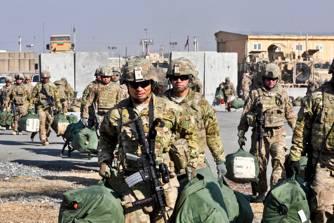 U.S. Army Master Sgt. Duane Perez, foreground, carries duffel bags and ...