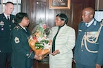 Maj. Gen. Patrick Murphy, the adjutant general of New York, looks on as Sgt 1st Class Sandra Mood presents a bouquet to Matshipo Phala, the wife of Brig. Gen. Mashoro Phala, the South African defense attaché to the United States, on Dec. 18, 2013.