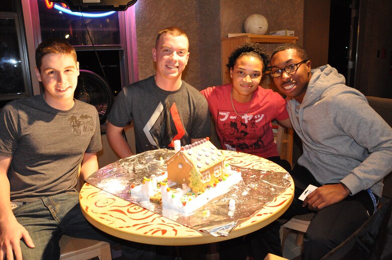 PETERSON AIR FORCE BASE, Colo. – Airman 1st Class Brett Wells, Senior Airman Matthew Reynolds, Airman 1st Class Maricel DaCosta, and Senior Airman Wayne Harding, 21st Communications Squadron Airmen, pose with their winning gingerbread house during the first-ever gingerbread house building competition Dec. 18 at the Cyber Cafe. The team was selected best among eight different entries and each won a $50 gift card to the Exchange. (U.S. Air Force photo/1st Lt. Stacy Glaus)