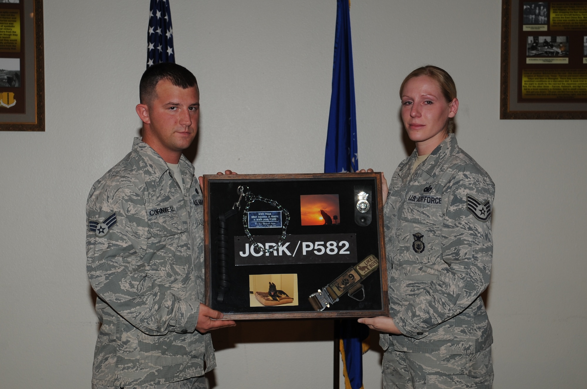 GOODFELLOW AIR FORCE BASE, Texas -- Senior Airman Zachary Cornwell, 17th Security Forces Squadron military work dog handler, presents Staff Sgt. Amanda Goetz, 17th SFS MWD handler, with a shadow box in honor of her MWD Jork during a memorial ceremony for him Dec. 18 at the Event Center. Jork passed away Nov. 21. (U.S. Air Force photo/ Staff Sgt. Laura R. McFarlane)