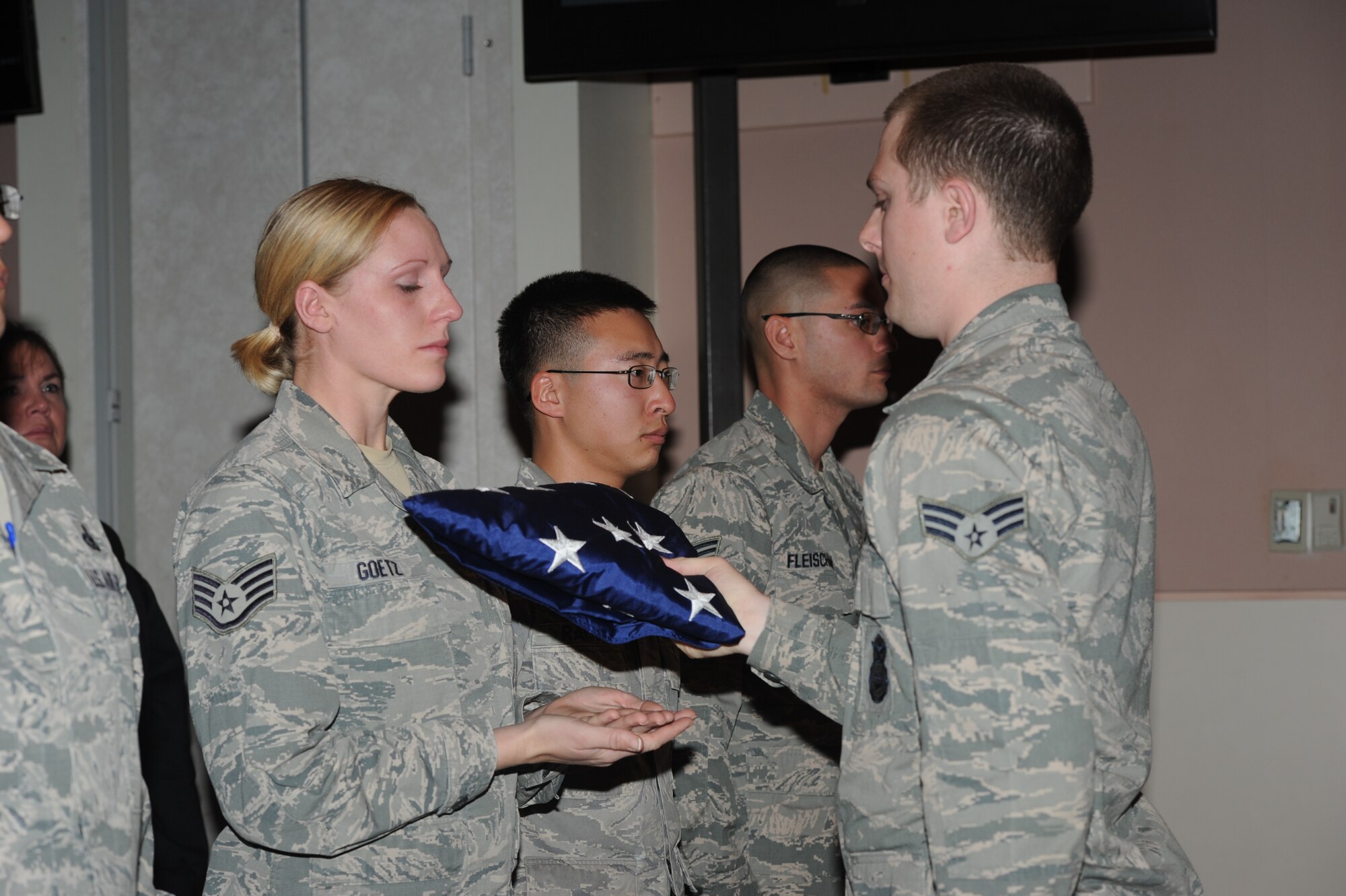 GOODFELLOW AIR FORCE BASE, Texas -- Senior Airman Tyler Beddes, 17th Security Forces Squadron military work dog handler, presents Staff Sgt. Amanda Goetz, 17th SFS MWD handler, with a flag folded in honor of her MWD, Jork, during a memorial ceremony for him Dec. 18 at the Event Center. Jork passed away Nov. 21. (U.S. Air Force photo/ Staff Sgt. Laura R. McFarlane)