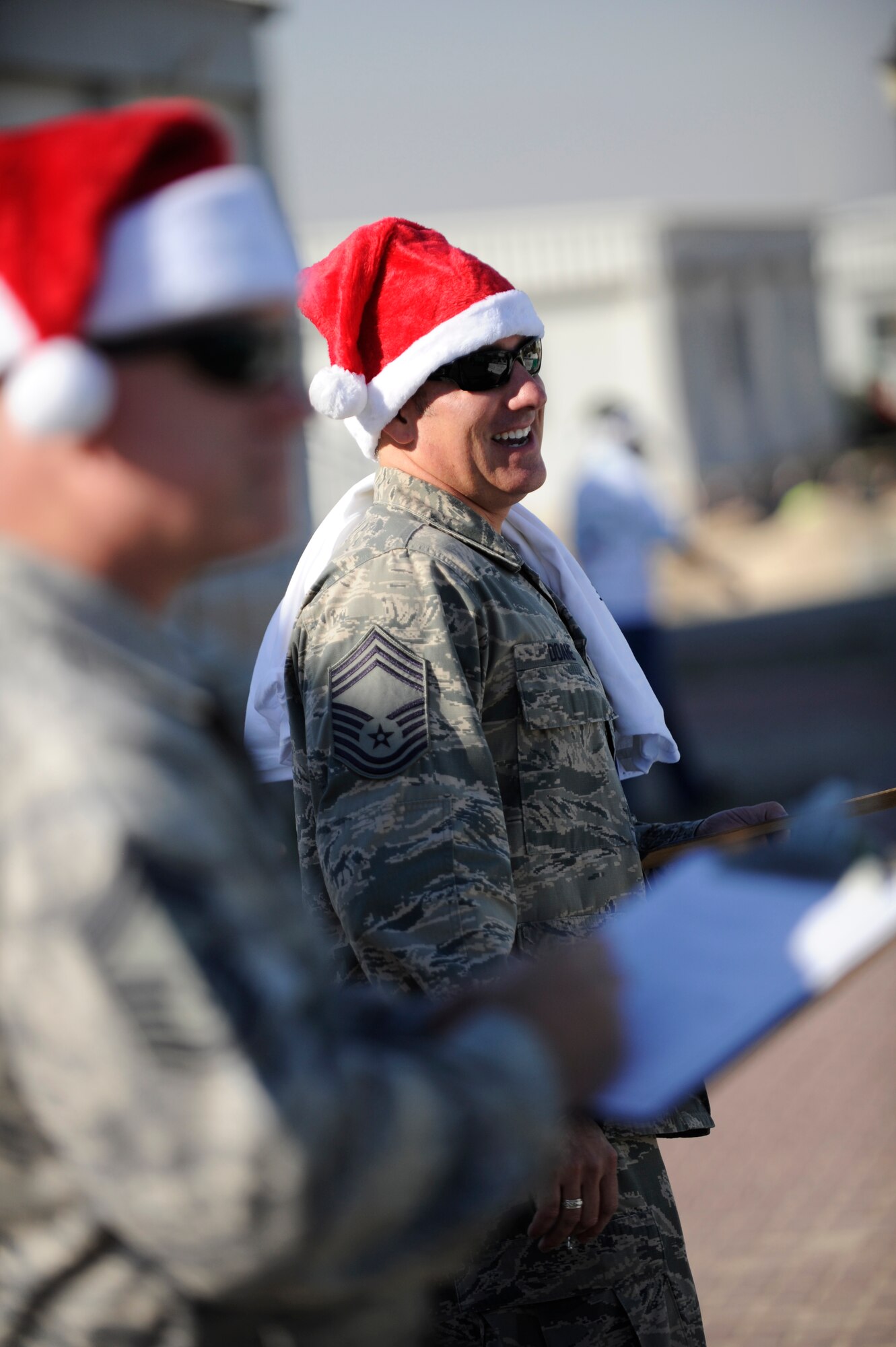 Chief Master Sgt. Shawn Doane, Chief Enlisted Manager for the 386th Expeditionary Force Support Squadron, laughs as he takes in the sights and sounds of the holiday parade held on Dec. 25 on The Rock.  Chief Doane was one of three judges who rated the different entries created by the different organizations on the base.  (U.S. Air Force photo by Senior Master Sgt. Burke Baker)
