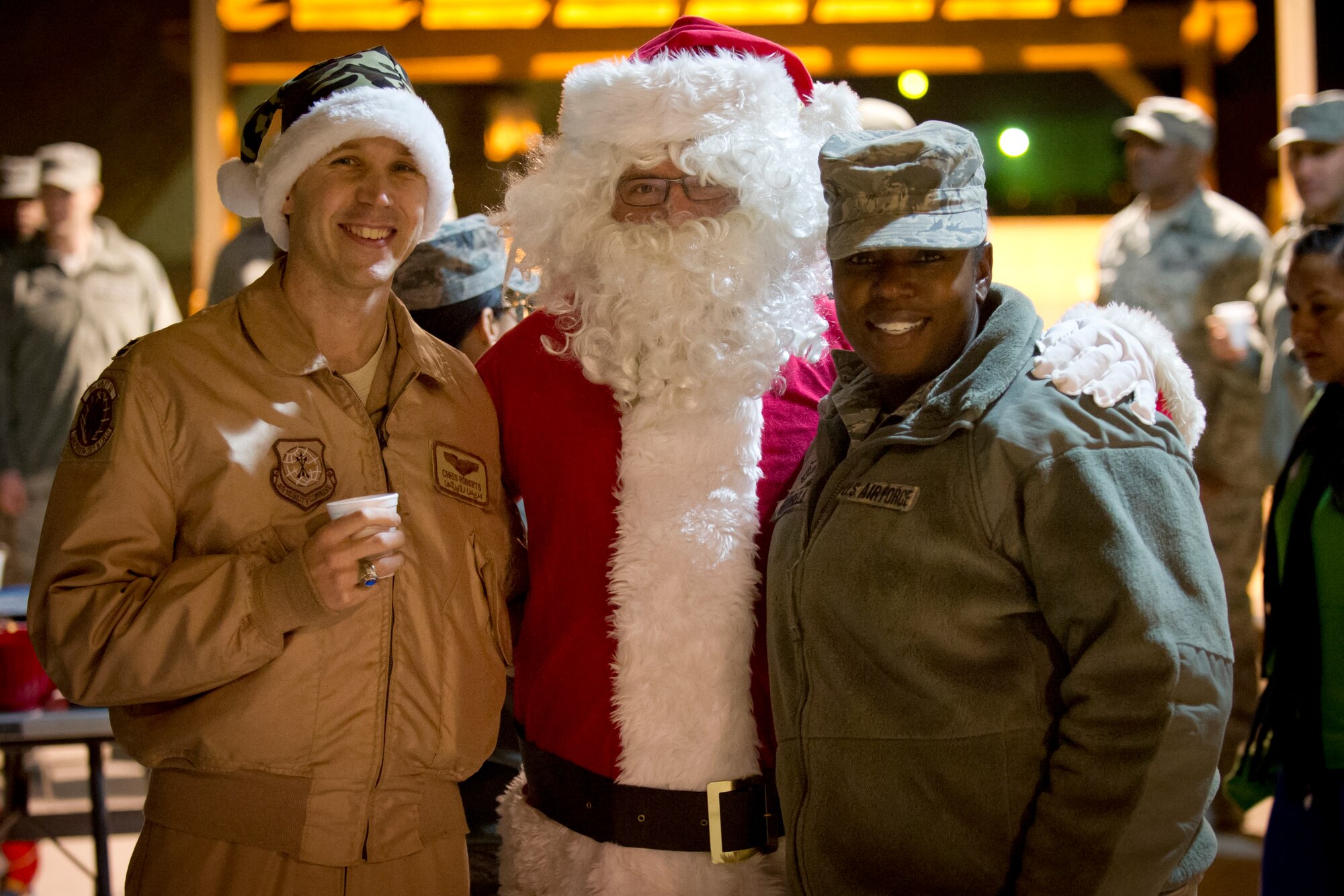 Capt. Chris Roberts and Master Sgt. Widlene Harrell , both with the 386th Air Expeditionary Wing, share a cup of hot cocoa and good cheer with Santa Claus during the base tree lighting ceremony held on The Rock.  The tree lighting was orchestrated by the base Top-3 council.  (U.S. Air Force photo by Senior Master Sgt. Burke Baker)