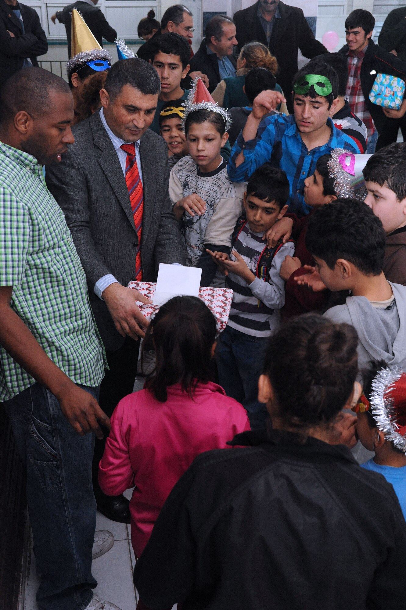 Yunus Cinkir, Seyhan Isitme elementary school principal, hands out one of 78 gifts donated by the Incirlik Air Base chapel community for a holiday party held at the school Dec. 26, 2013, in Adana, Turkey. Seyhan Isitme is one of eight schools for hearing impaired children in Turkey. Some of the students at the school live more than 100 kilometers away and remain at the school for the entirety of the school week. (U.S. Air Force photo by 1st Lt. David Liapis/Released)
