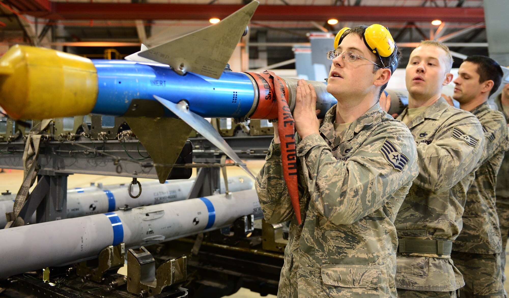 Staff Sgt. Jared Schiffman, Staff Sgt. Brady Fender and Senior Airman Adam Hennek, 48th Munitions Squadron F-15 maintenance team chiefs, carry an AIM-9 munition during the Royal Air Force Lakenheath, England, Load Crew of the Quarter competition, Dec. 19, 2013. Airmen from the 48th MUNS were competing against the clock to beat their fastest time. (Air Force photo by Airman 1st Class Dawn M. Weber/Released)