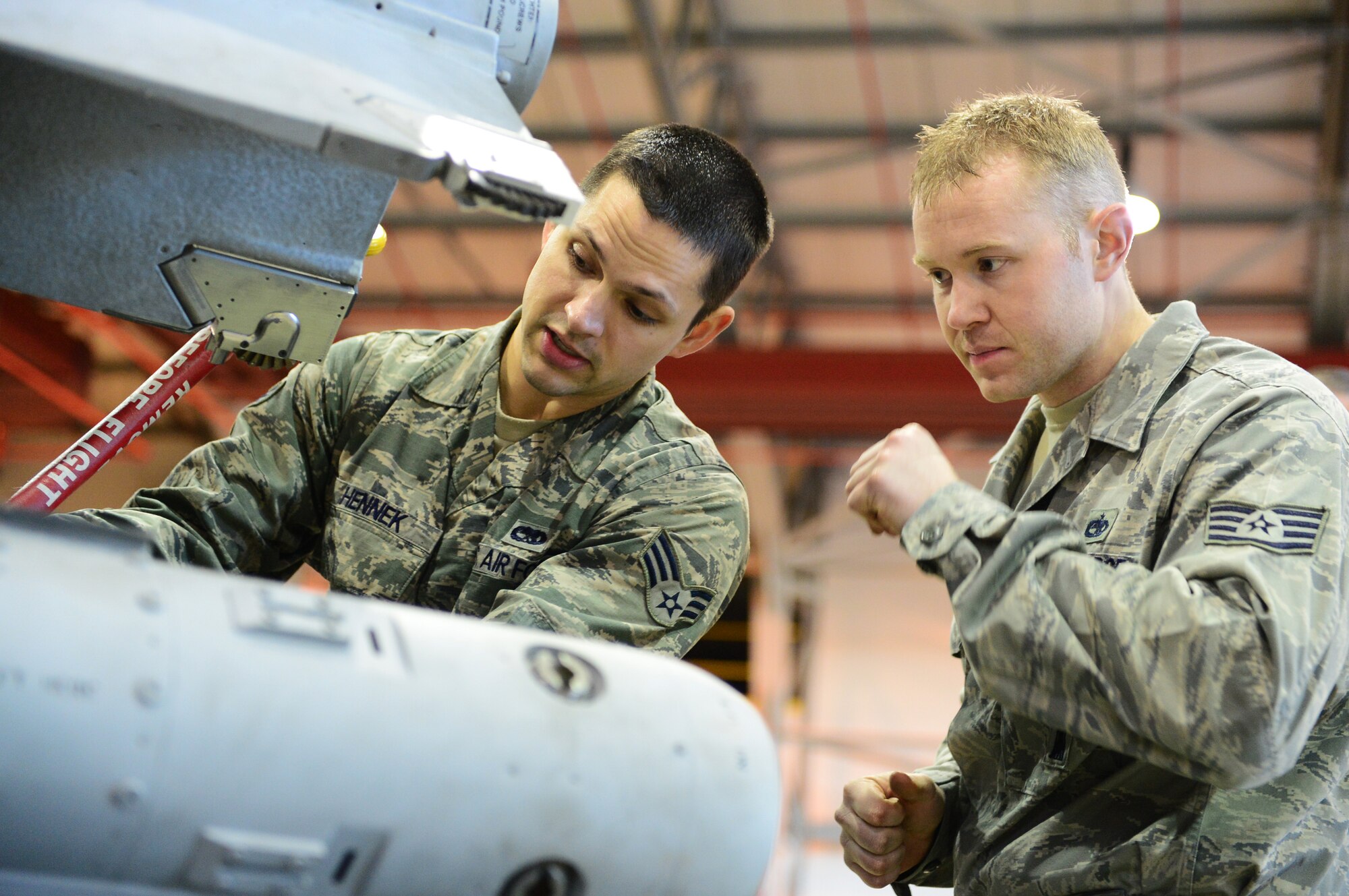 Senior Airman Adam Hennek and Staff Sgt. Brady Fender, 48th Munitions Squadron F-15 maintenance team chiefs, inspect an AIM-9 munition during the Royal Air Force Lakenheath, England, Load Crew of the Year competition, Dec. 19, 2013. Airmen from the 48th MUNS were competing against the clock to beat their fastest time. (Air Force photo by Airman 1st Class Dawn M. Weber/Released)