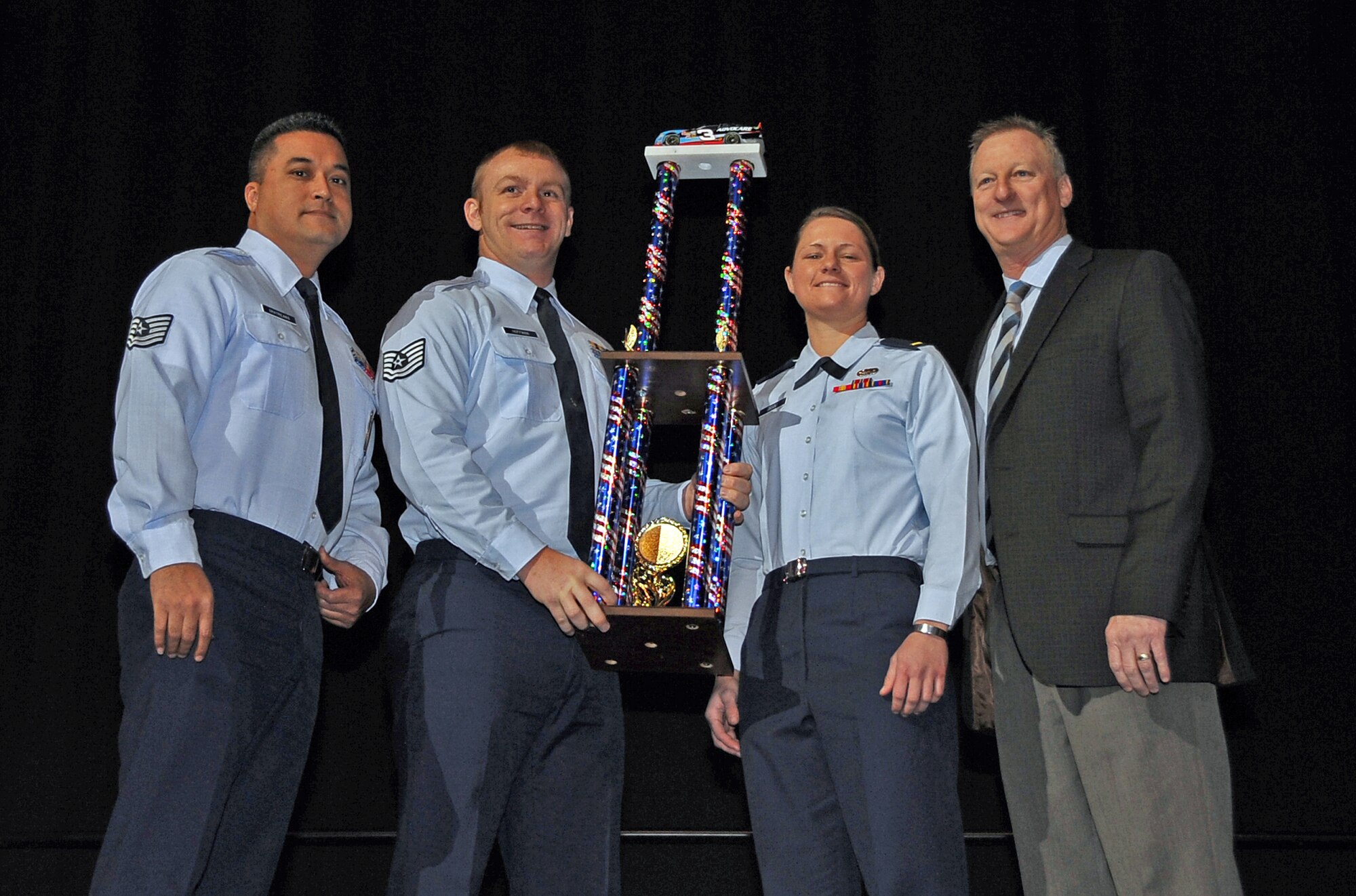 (Left to Right) Tech. Sgt. Terry Gatreaks, Tech. Sgt. Robert Hoffman and 2nd Lt. Dayna Grant from the 2nd Munitions Squadron and Mike Vaught, Advocare director of corporate sponsorships, pose with the Airmen pit crew challenge trophy at the Centurylink Center in Bossier City, La., Dec. 30, 2013. The 2nd MUNS team was presented the trophy for besting seven other Barksdale teams, the Arizona Wildcats football team and the Boston College football team. (U.S. Air Force photo/Staff Sgt. Jason McCasland)