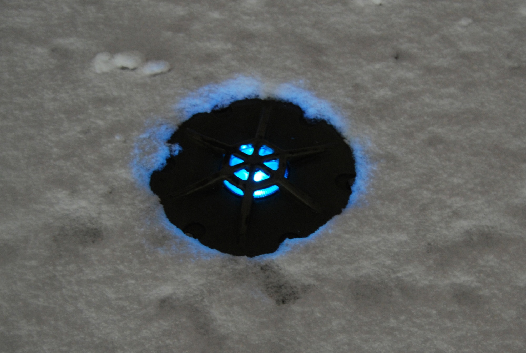 An airfield taxiway light is illuminated and surrounded by snow during a snowstorm at Bagram Airfield, Afghanistan, Dec. 29, 2013. Total snow accumulation was approximately 3 inches. (U.S. Air Force Photo by Capt. Brian Wagner/Released)