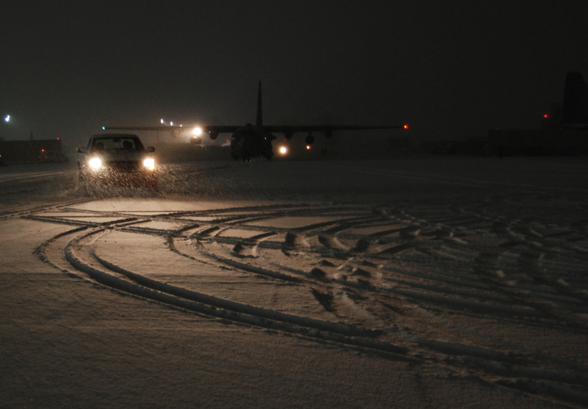 Airfield operations personnel plow a path for a taxiing C-130 Hercules during a snowstorm, Dec. 29, 2013 at Bagram Airfield, Afghanistan. Total snow accumulation was approximately 3 inches. (U.S. Air Force photo by Capt. Brian Wagner/Released)