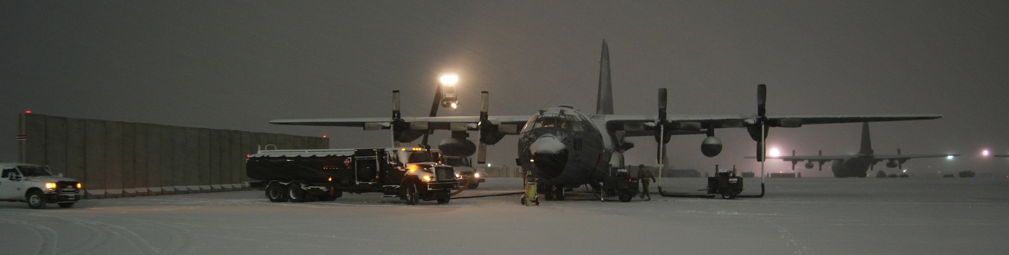 A de-icing team and fuels crew work to prepare a C-130 Hercules for a mission during a snowstorm Dec. 29, 2013 at Bagram Airfield, Afghanistan. Total snow accumulation was approximately 3 inches. (U.S. Air Force Photo by Capt. Brian Wagner/Released)