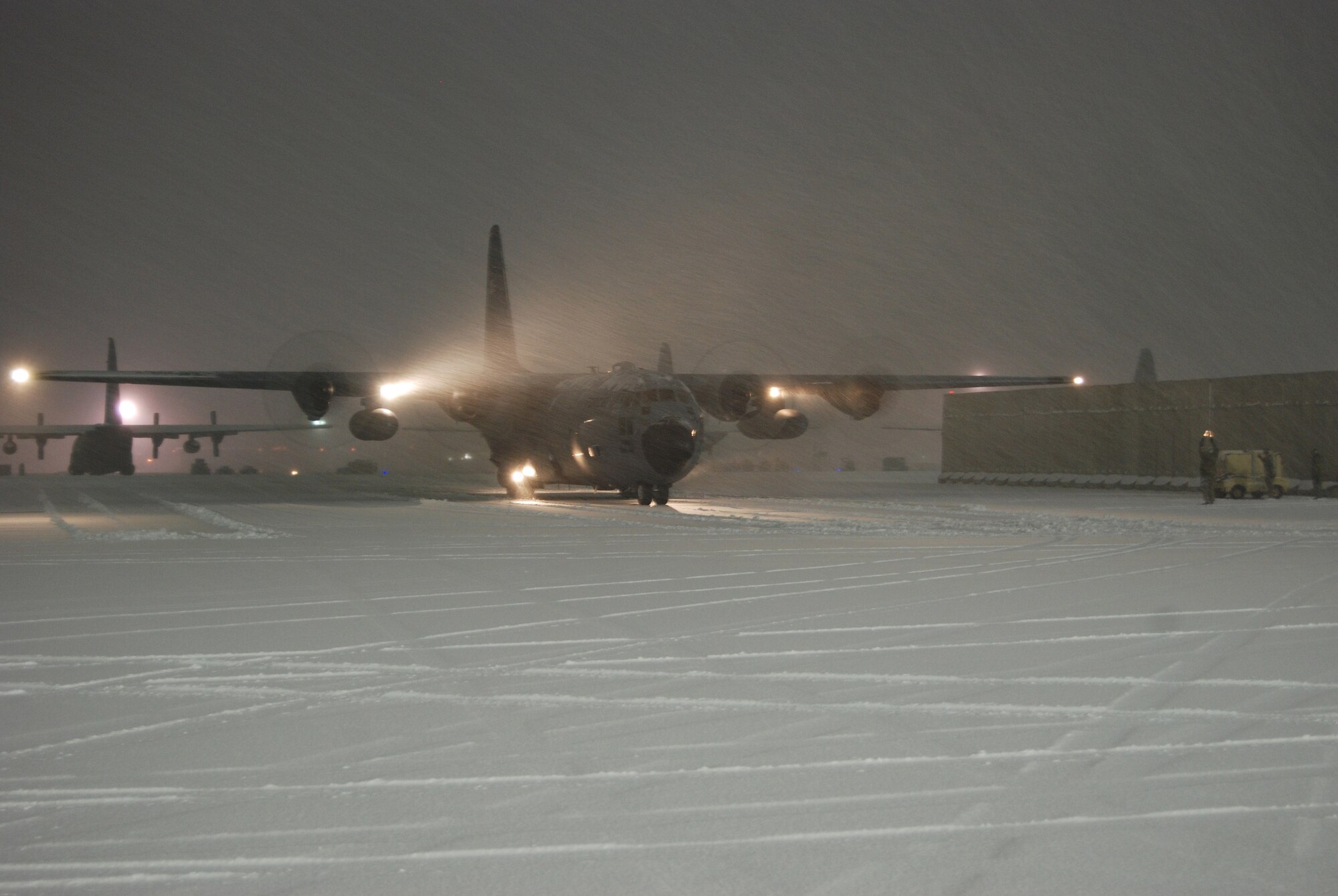 An Airman directs a C-130 Hercules into a parking spot during a snowstorm, Dec. 29, 2013 at Bagram Airfield, Afghanistan. Total snow accumulation was approximately 3 inches. (U.S. Air Force photo by Capt. Brian Wagner/Released)