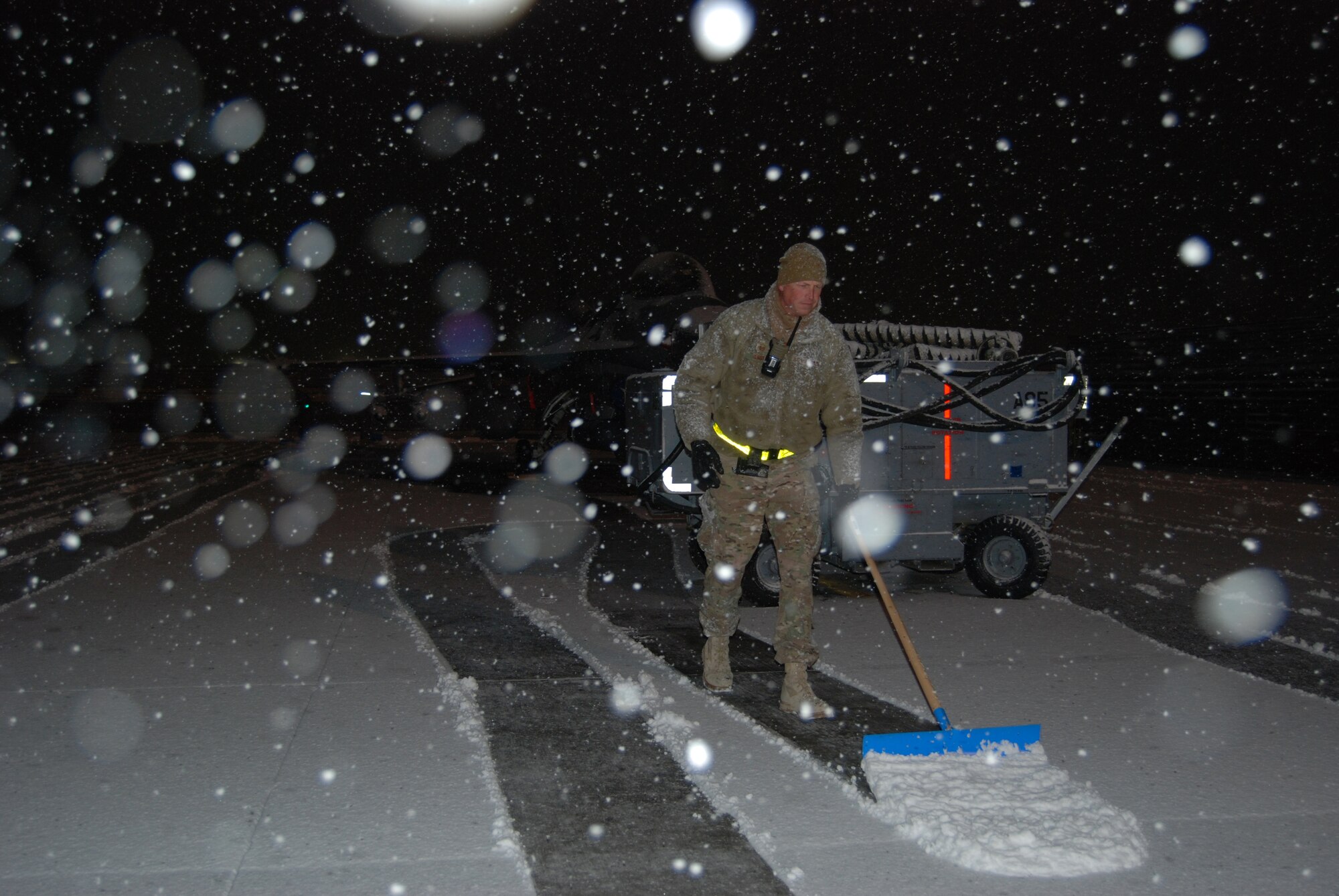 An Airman clears snow in front of a F-16 Fighting Falcon during a snowstorm, Dec. 29, 2013 at Bagram Airfield, Afghanistan. Total snow accumulation was approximately 3 inches. (U.S. Air Force photo by Capt. Brian Wagner/Released)
