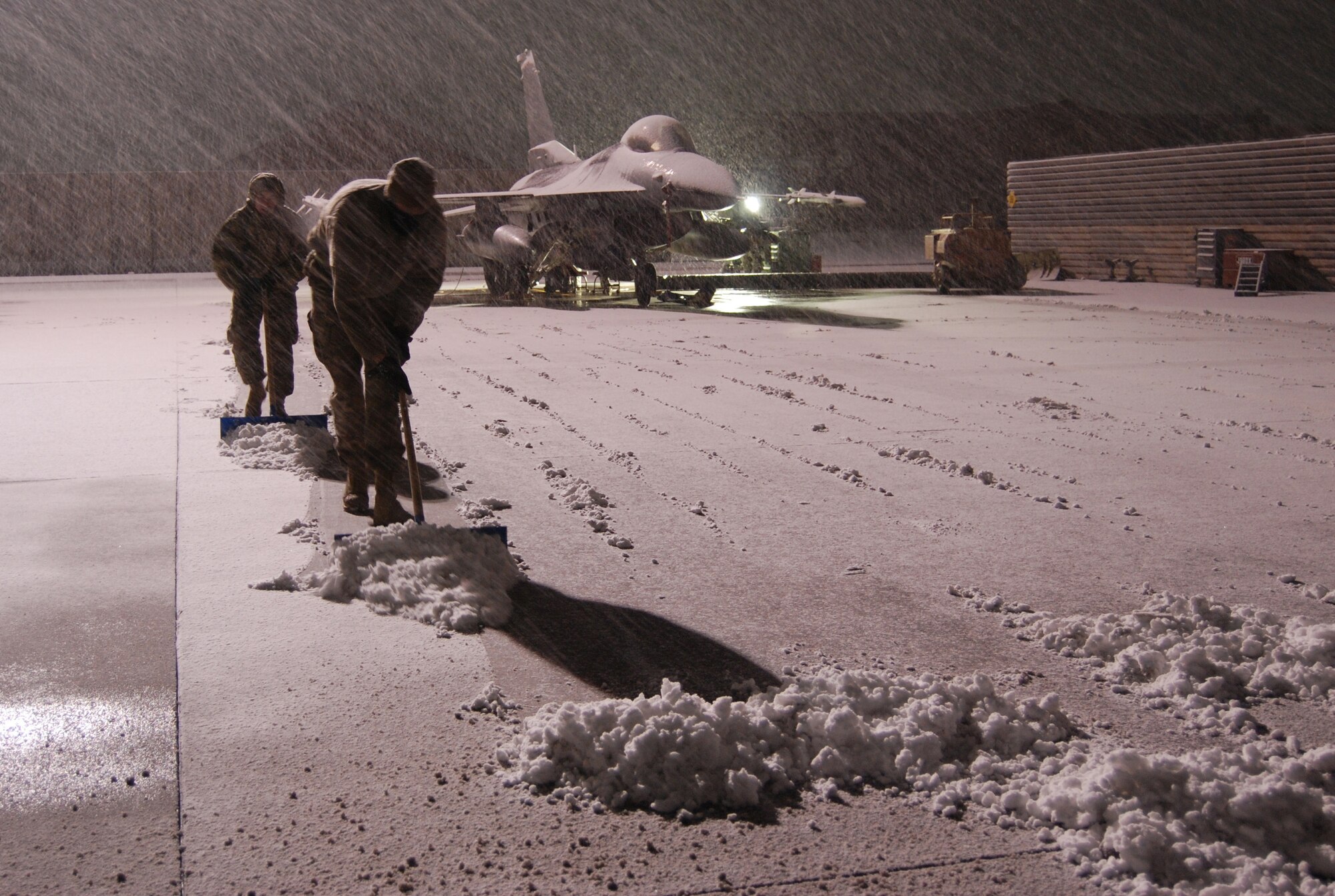 Airmen clear snow near a F-16 Fighting Falcon during a snowstorm, Dec. 29, 2013 at Bagram Airfield, Afghanistan. Total snow accumulation was approximately 3 inches. (U.S. Air Force Photo by Capt. Brian Wagner/Released)