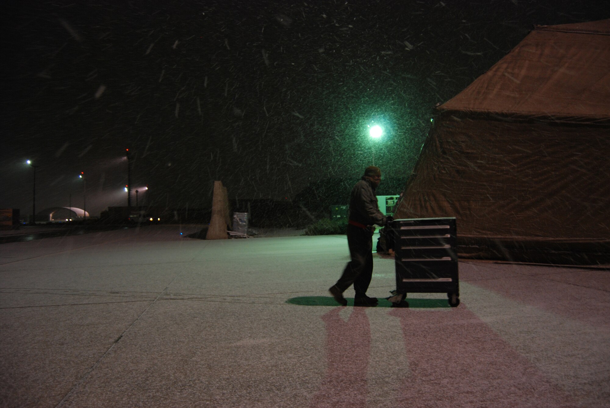 A 455th Expeditionary Maintenance Group Airman pushes a tool box off the flightline during a snowstorm at Bagram Airfield, Afghanistan, Dec. 29, 2013. Total accumulation was approximately 3 inches. (U.S. Air Force Photo by Capt. Brian Wagner/Released)