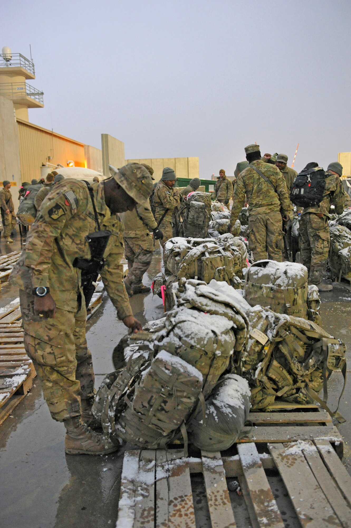 Soldiers from the Louisiana National Guard grab their snow-covered ruck sacks as they prepare to board a flight home from Bagram Airfield, Afghanistan, December 29, 2013. The soldiers were completing a nine month deployment.(U.S. Air Force photo by Senior Master Sgt. Gary J. Rihn/Released)