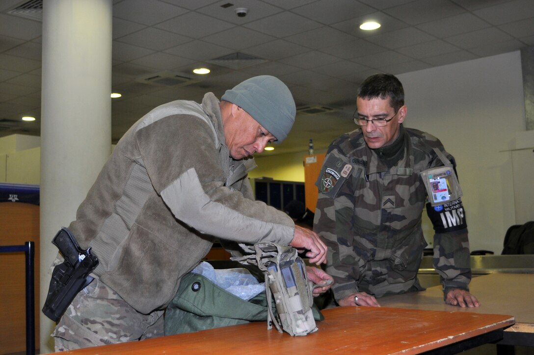 A French security officer and member of the International Military Police monitors U.S. Army Sgt. 1st Class Gerard Paulino for contraband during screening in Kabul, Afghanistan, Dec. 28, 2013. Paulino is assigned to Headquarters Company, 1st Battalion, 294th Infantry Regiment, Guam Army National Guard. 