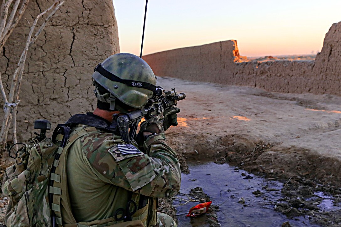 A U.S. Special Forces Operation Detachment-Alpha soldier uses his weapon's optic lens to scan the area as Afghan national commandos conduct a clearing operation in Mandozai village in the Maiwand district of Afghanistan's Kandahar province, Dec. 27, 2013. U.S. soldiers assisted the Afghan commandos.