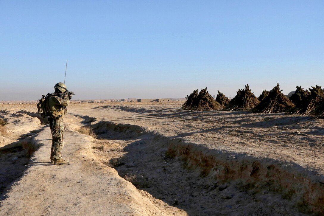 A U.S. Special Forces Operation Detachment Alpha soldier scans the area as Afghan  commandos conduct a clearing operation in Mandozai village in the Maiwand district in Afghanistan's Kandahar province, Dec. 27, 2013.