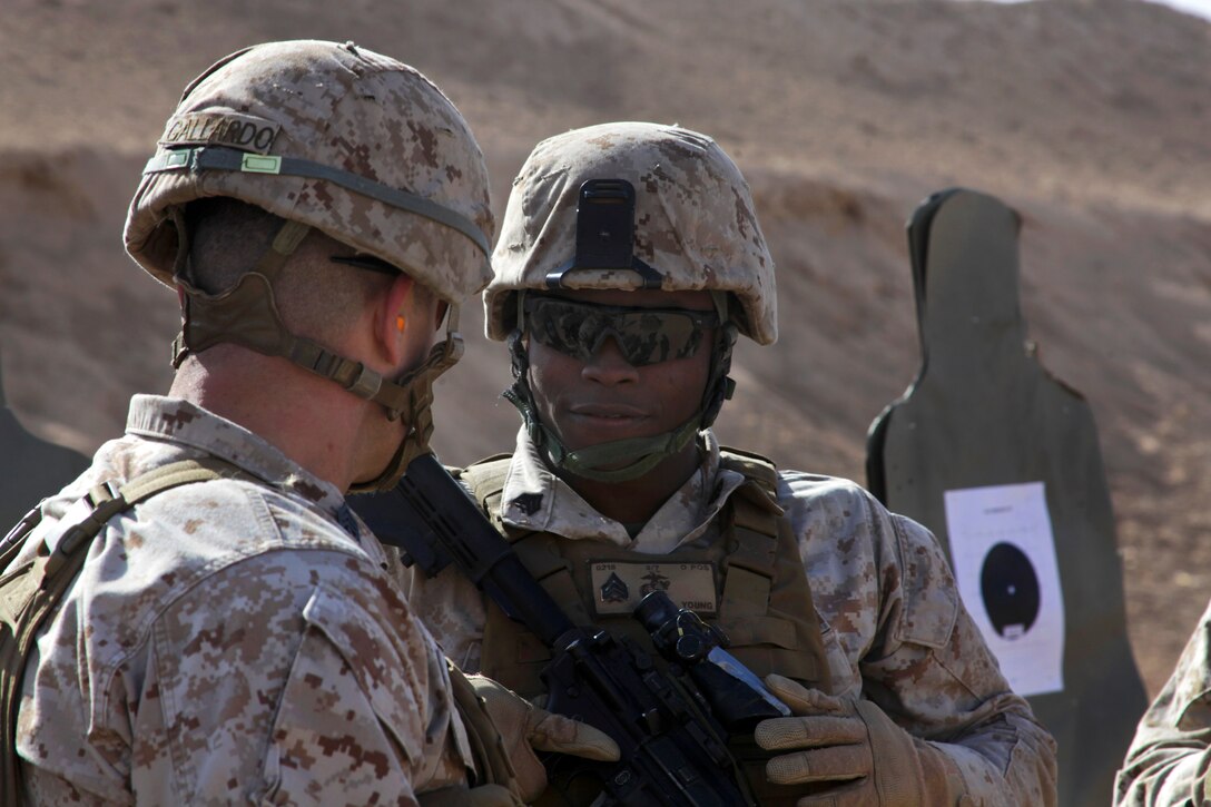 U.S. Marine Corps Sgt. Dominique Young, right, speaks with U.S. Marine Corps 1st Sgt. Juan Gallardo during a battle sight zero at a range on Camp Leatherneck in Helmand province, Afghanistan, Dec. 22, 2013. Young, an intelligence specialist, and Gallardo, a senior enlisted advisor, are assigned to Headquarters and Service Company, 3rd Battalion, 7th Marine Regiment.