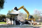 TSgt Carl White Jr., 147th Civil Engineers, 147th Fighter Wing, Texas Air National Guard, raises the bucket on the Komarsu excavator to reach out and collapse the front of a dilapadated house in that was identified by local law enforcement as being used for illicit drug activity, Harlingen, Texas, Dec. 16, 2013. Texas Joint Counterdrug Task Force's Operation Crackdown destroys drug havens in partnership with city officials and law enforcement agencies.