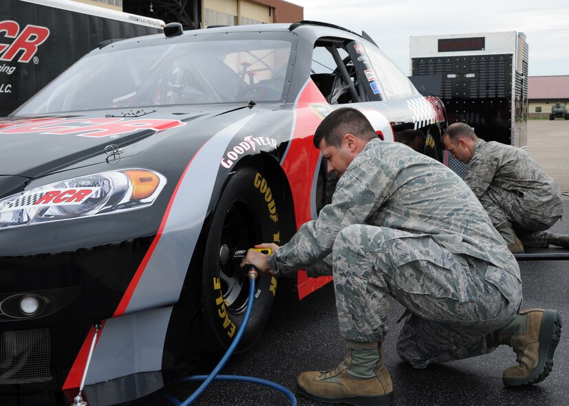 Col. Andrew Gebara, 2nd Bomb Wing commander, simulates removing a tire during a pit crew challenge at Hoban Hall on Barksdale Air Force Base, La., Dec. 28, 2013. Gebara used a pneumatic drill to unscrew and tighten five lug nuts on two tires. (U.S. Air Force photo/Senior Airman Joseph A. Pagán Jr.)

