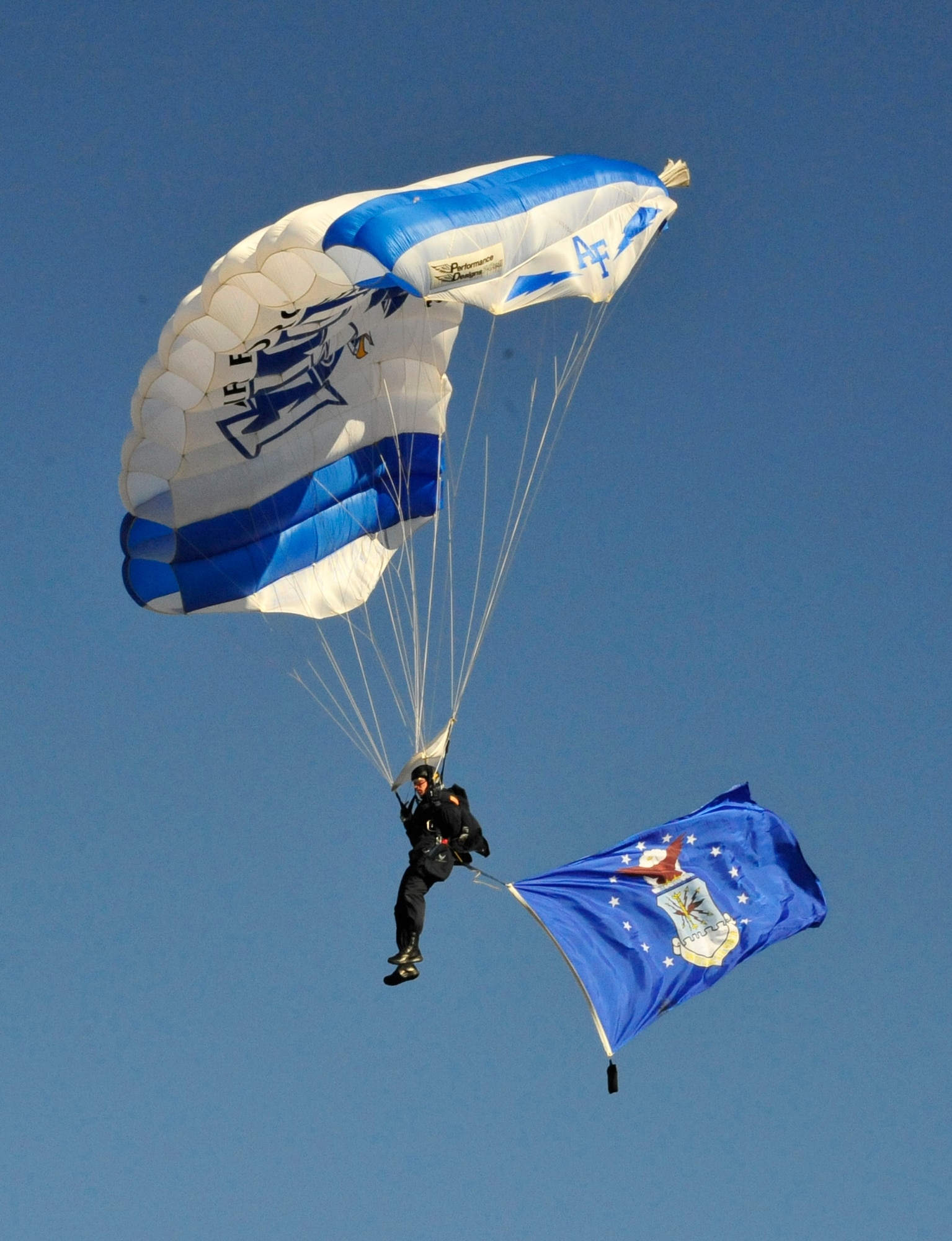 An Air Force Wings of Blue member glides down with the service's flag Friday at the Litchfield Golf Course in Litchfield Park, Ariz. Wings of Blue members practiced jumping in preparation for Saturday's Buffalo Wings Bowl at Arizona State University's Sun Devil Stadium in Tempe, Ariz. (U.S. Air Force photo/Senior Airman Grace Lee)