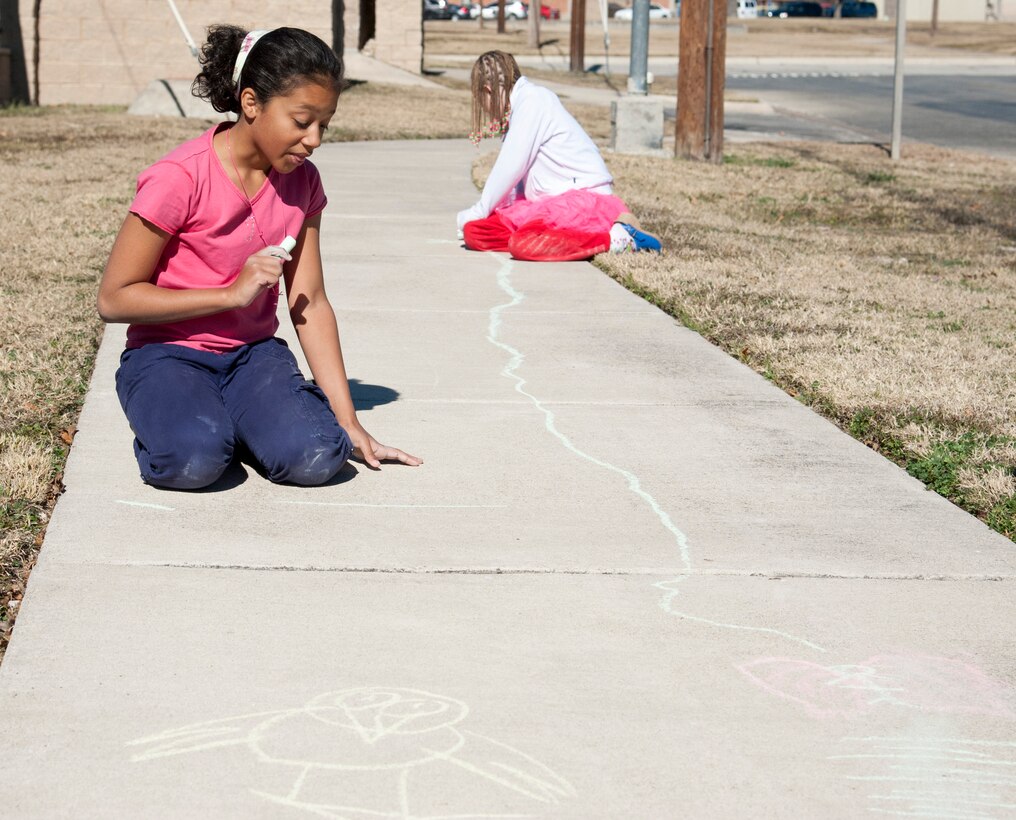 Juliett Bostrom and Kayla Reifel, enjoy their new year’s eve decorating a sidewalk with chalk on Laughlin Air Force Base, Texas, December 31, 2013. They developed a new version of hopscotch in which you tell a story by deciding which way you want to go. (U.S. Air Force photo/Airman 1st Class Jimmie D. Pike)
