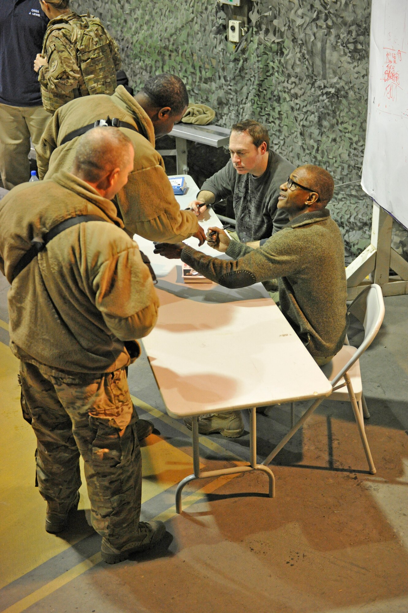 Comedians Rob Maher and Tommy Davidson sign autographs after their show at Bagram Airfield, Afghanistan, Dec. 31, 2013. The two performed a comedy routine for deployed Service members on New Year's Eve.(U.S. Air Force photo by Senior Master Sgt. Gary J. Rihn/Released)