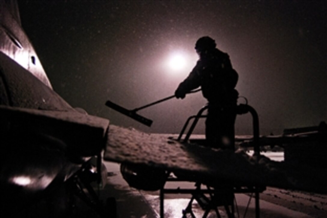 A U.S. airman clears a few inches of snow off an F-16 Fighting Falcon during the winter's first snowfall on Bagram Airfield, Afghanistan, Dec. 29, 2013.