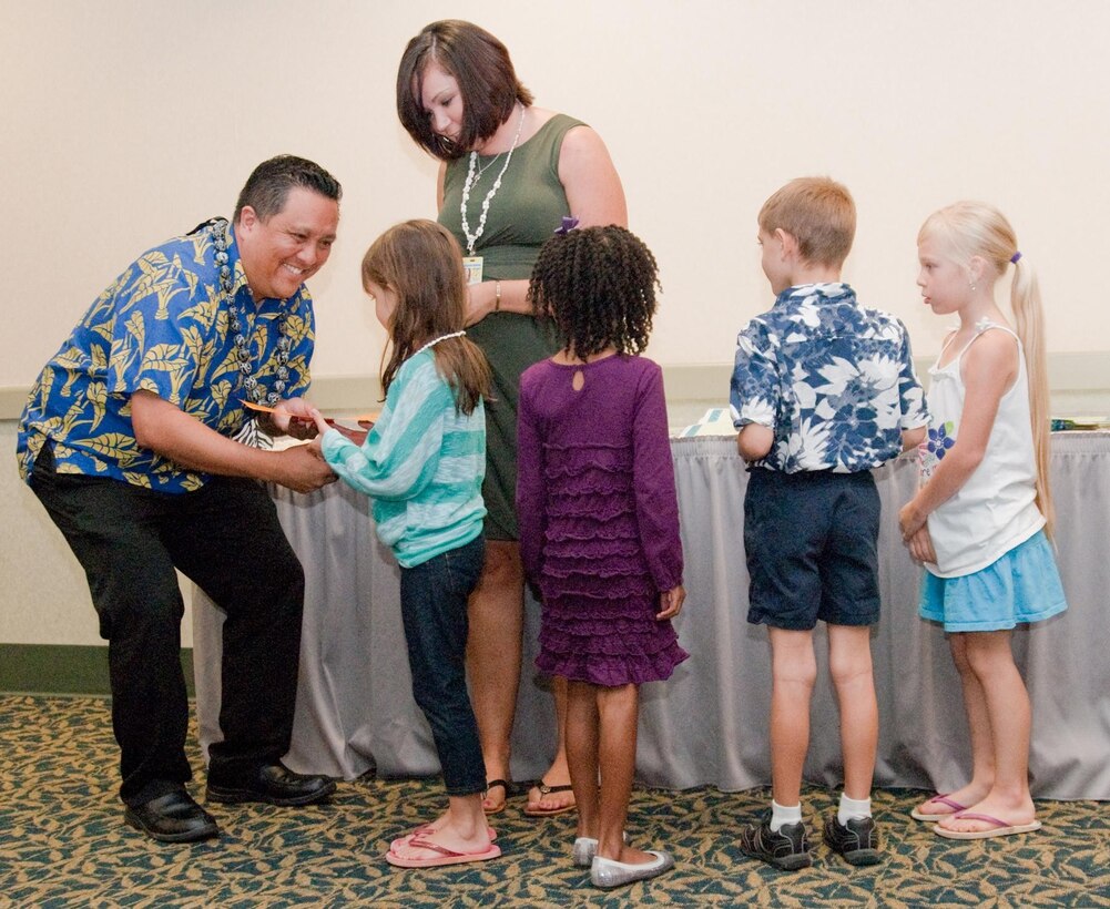 MARINE CORPS BASE HAWAII - Mokapu Elementary School Principal Keoni Wilhelm and Sarah-Beth Alvarez, the acting president of the Mokapu Parent Teacher Association, present certificates and prizes to the winners of the “The Magic of a Moment” Reflections Award Presentation in the Fairways Ballroom at the Kaneohe Klipper Golf Course, Jan. 25, 2013. Mokapu student Kendall Larson placed second in the Intermediate Visual Arts category, and took first, second and third place in the Intermediate Photography category. This is the second year Mokapu Elementary School has entered its students in the National PTA Reflections program competition. Students nationwide compete on the school and state levels by submitting written work, drawings, photos or films that fit a specific theme chosen each year. Students who qualify this year for the national competition will be flown to the 117th annual National PTA Convention and Exhibition in Cincinnati, with an adult. The winning student receives $800 and the student’s PTA receives $200 to fund enrichment in arts. “This is a beautiful program because it gets the kids so excited (about competing, winning and art),” said Kristy Ryan, Larson’s mother and a fundraising coordinator for the Mokapu PTA. (U.S. Marine Corps photo by Kristen Wong)