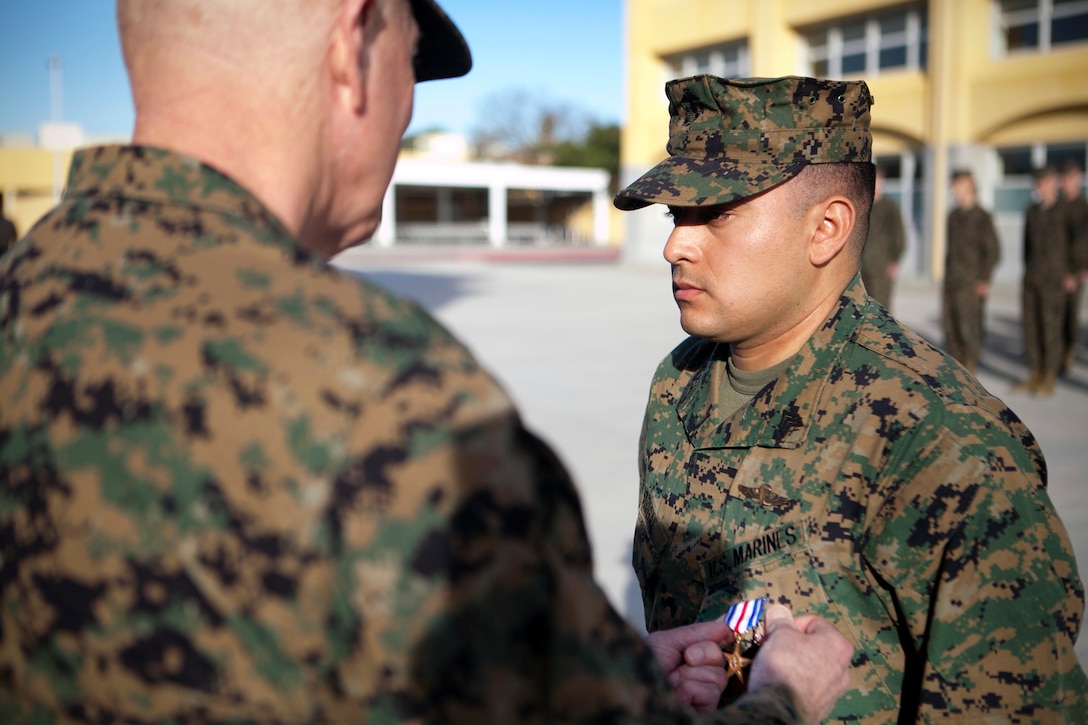 MARINE CORPS RECRUIT DEPOT, SAN DIEGO -- Lt. Gen. Steven A. Hummer, commander of Marine Forces Reserve and Marine Forces North, pins a Silver Star Medal on Sgt. Miguelange G. Madrigal, a radio chief with Supporting Arms Liaison Team G, 1st Air Naval Gunfire Liaison Company, I Marine Expeditionary Force Headquarters Group, aboard Marine Corps Recruit Depot, San Diego, Jan.  31, 2013. Madrigal, a native of Bakersfield, Calif., was awarded the nation’s third highest honor for his actions as a member of a squad patrol that was pinned down by insurgent fire. On Feb. 15, 2010, he repelled an enemy attack, rushed to save a fellow Marine, called in multiple fire-support missions, and called in a casualty evacuation. (U.S. Marine Corps photo by Cpl. Marcin Platek/Released)