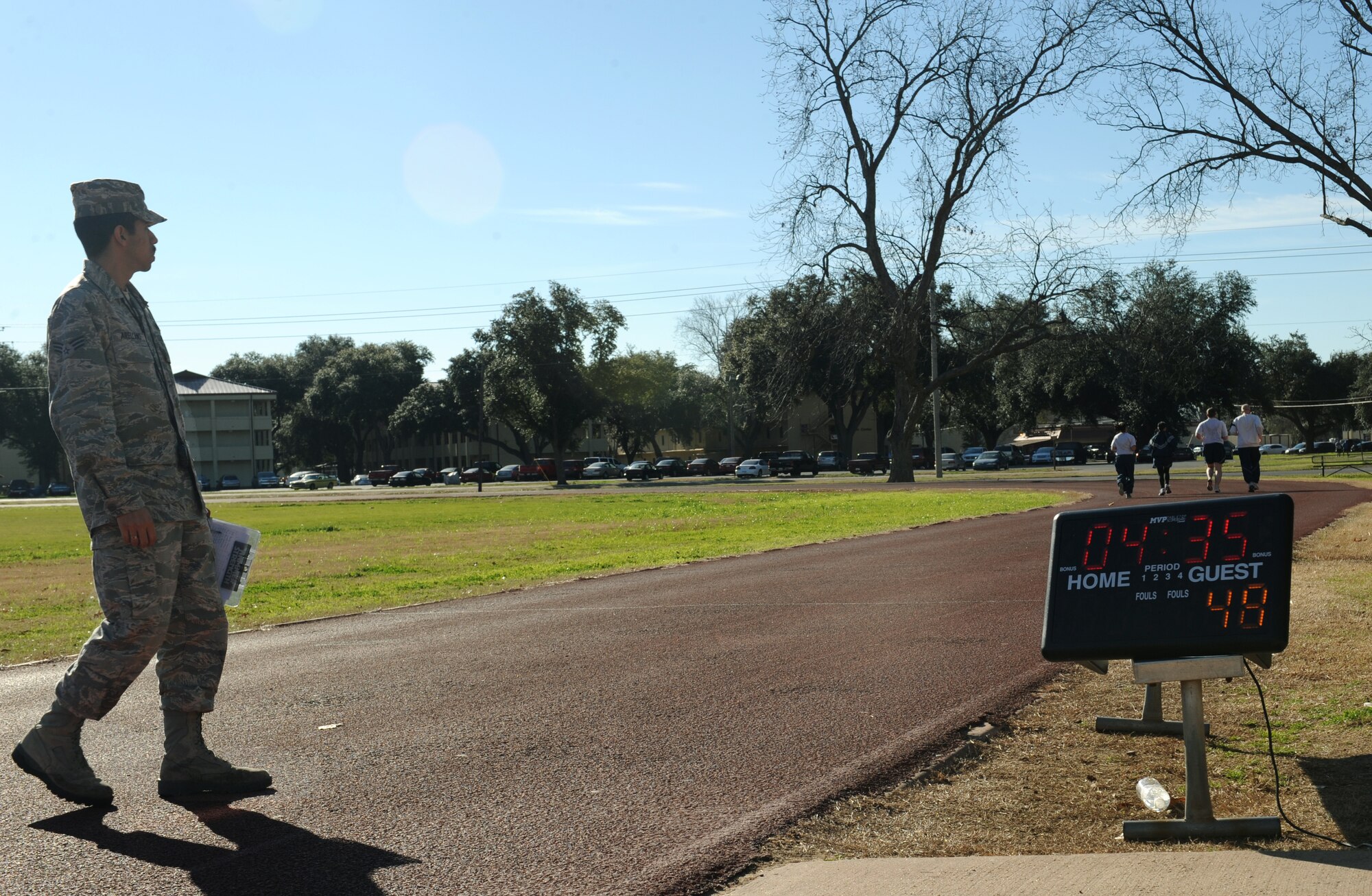 Senior Airman Braulio Arellano, 2nd Force Support Squadron fitness specialist, watches runners during a physical training test on Barksdale Air Force Base, La., Feb. 1. Fitness specialists clean equipment, administer PT tests and build fitness programs for base personnel. (U.S. Air Force photo/Airman 1st Class Benjamin Gonsier)