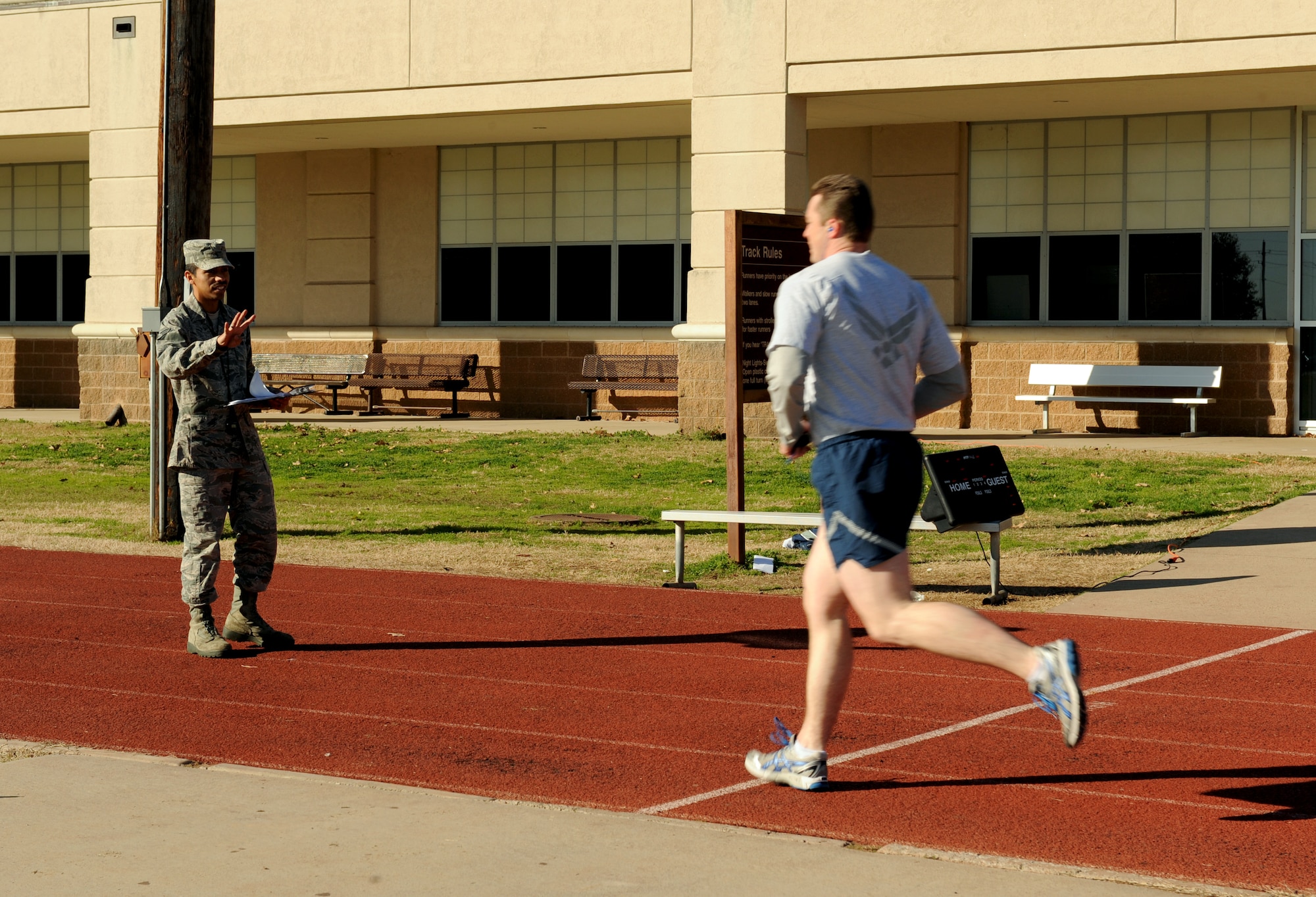 Senior Airman Braulio Arellano, 2nd Force Support Squadron fitness specialist, signals to a runner what lap he is on during his physical training test on Barksdale Air Force Base, La., Feb. 1. Fitness specialists clean equipment, administer PT tests and build fitness programs for base personnel. (U.S. Air Force photo/Airman 1st Class Benjamin Gonsier)