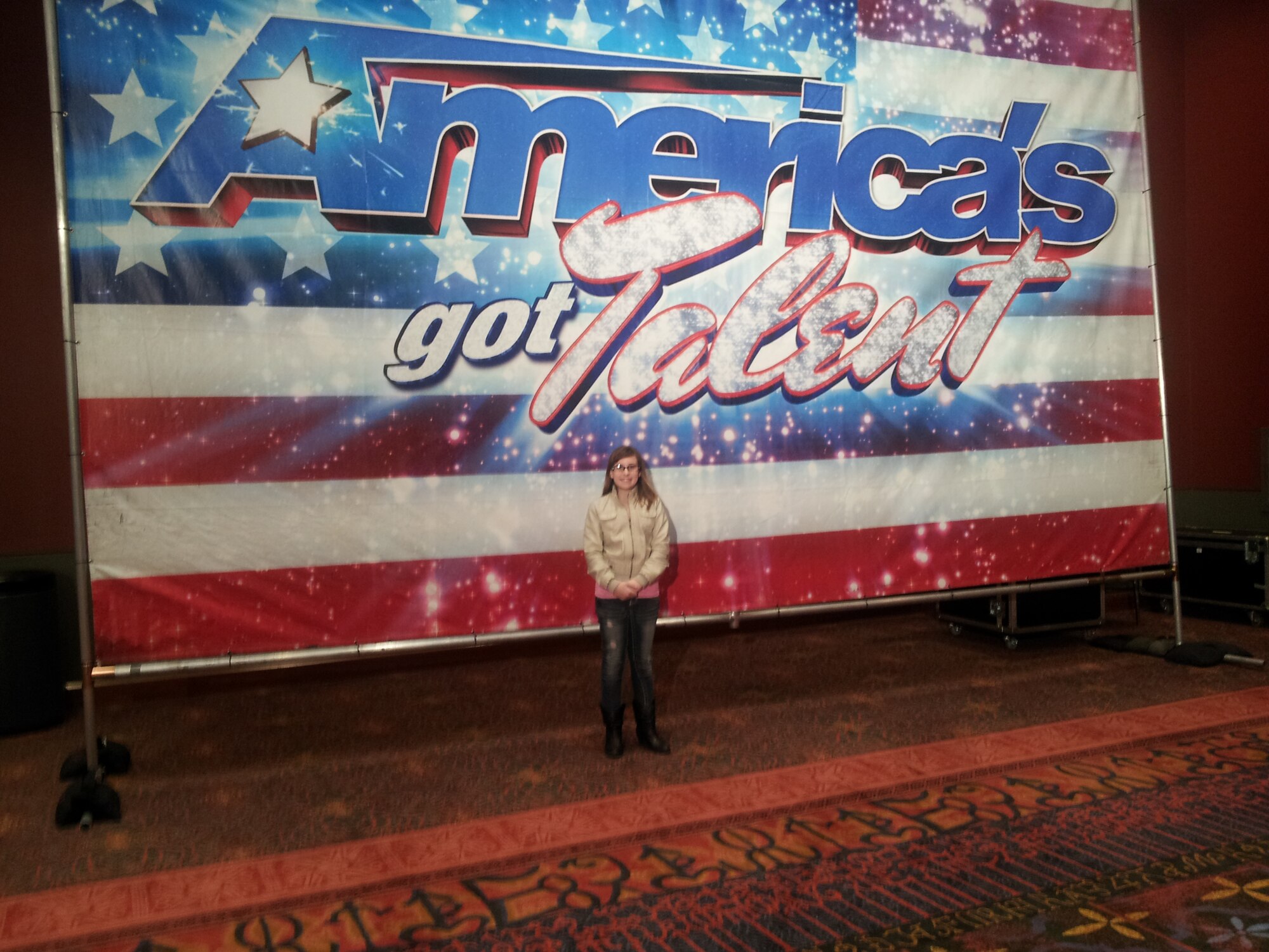 Amber Buss, 12-year-old daughter of Tech Sgt. Shane Buss of the 47th Equal Opportunity office, stands in front of an America’s Got Talent banner in San Antonio, Texas, Jan. 12, 2013. She auditioned for the show and is currently awaiting a call back for a second audition. (Contributed Photo)